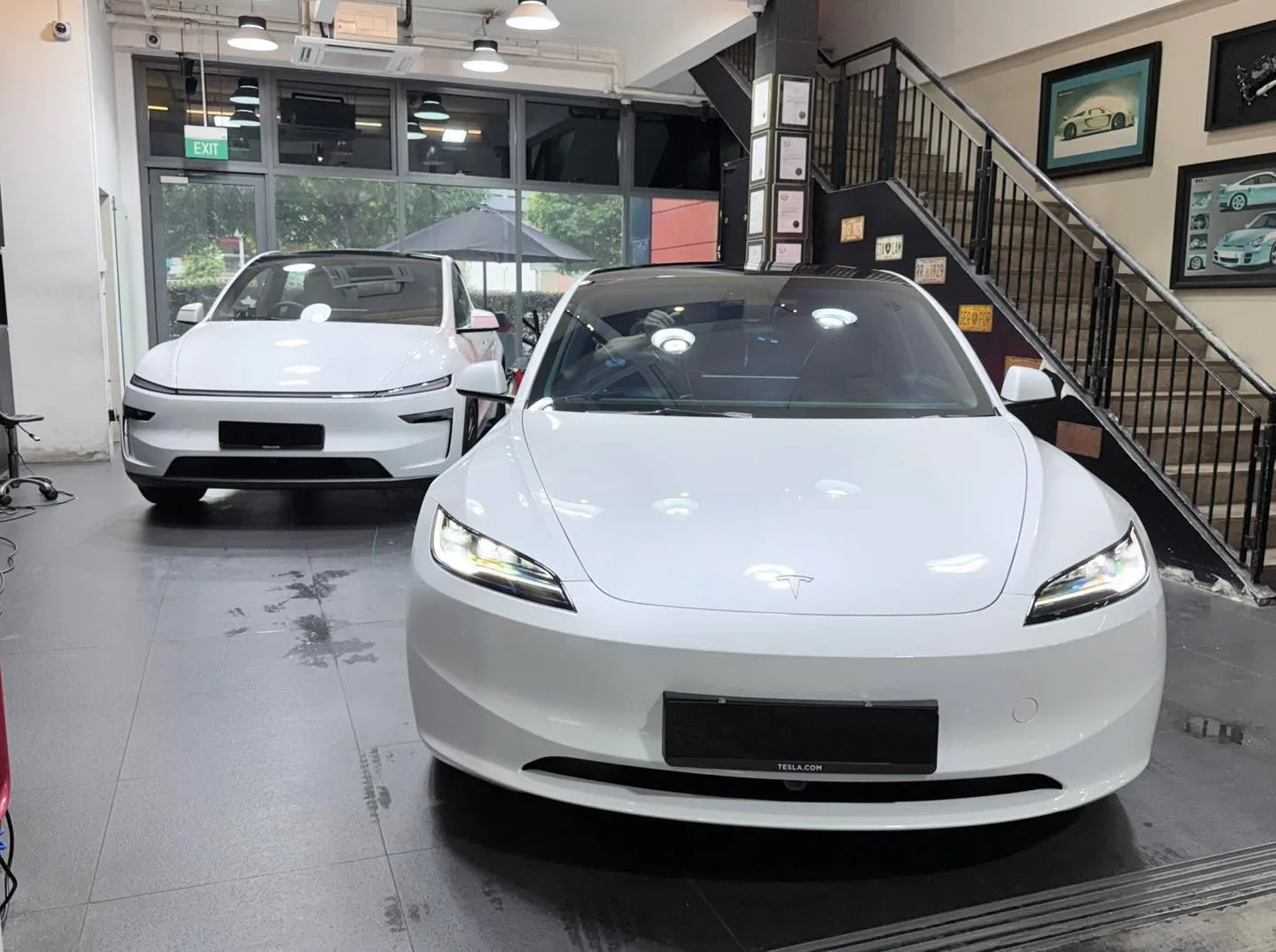 A white sedan viewed from the front in an indoor workshop space.