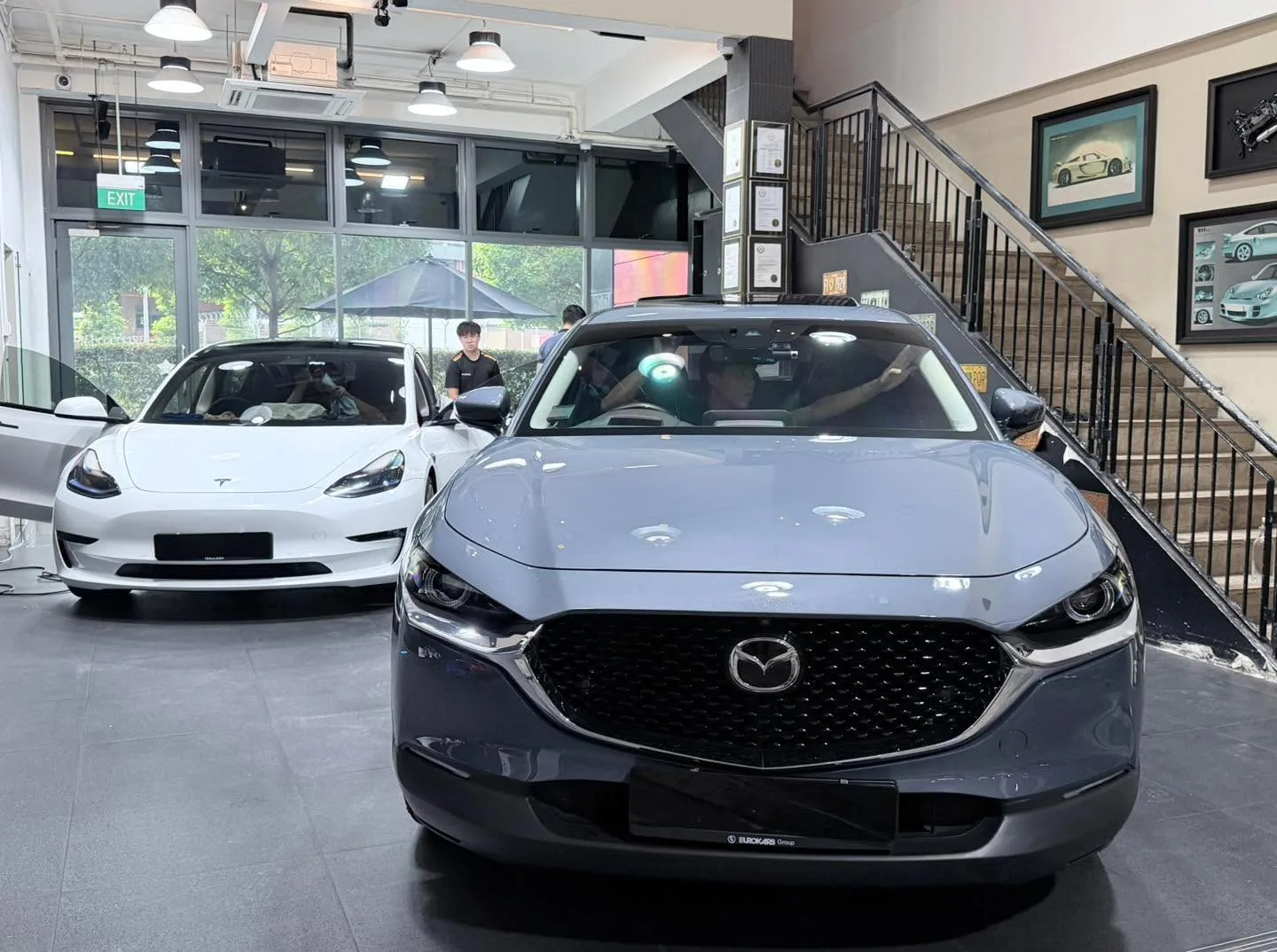 A white sedan and grey SUV with kidney grille in the workshop during service.