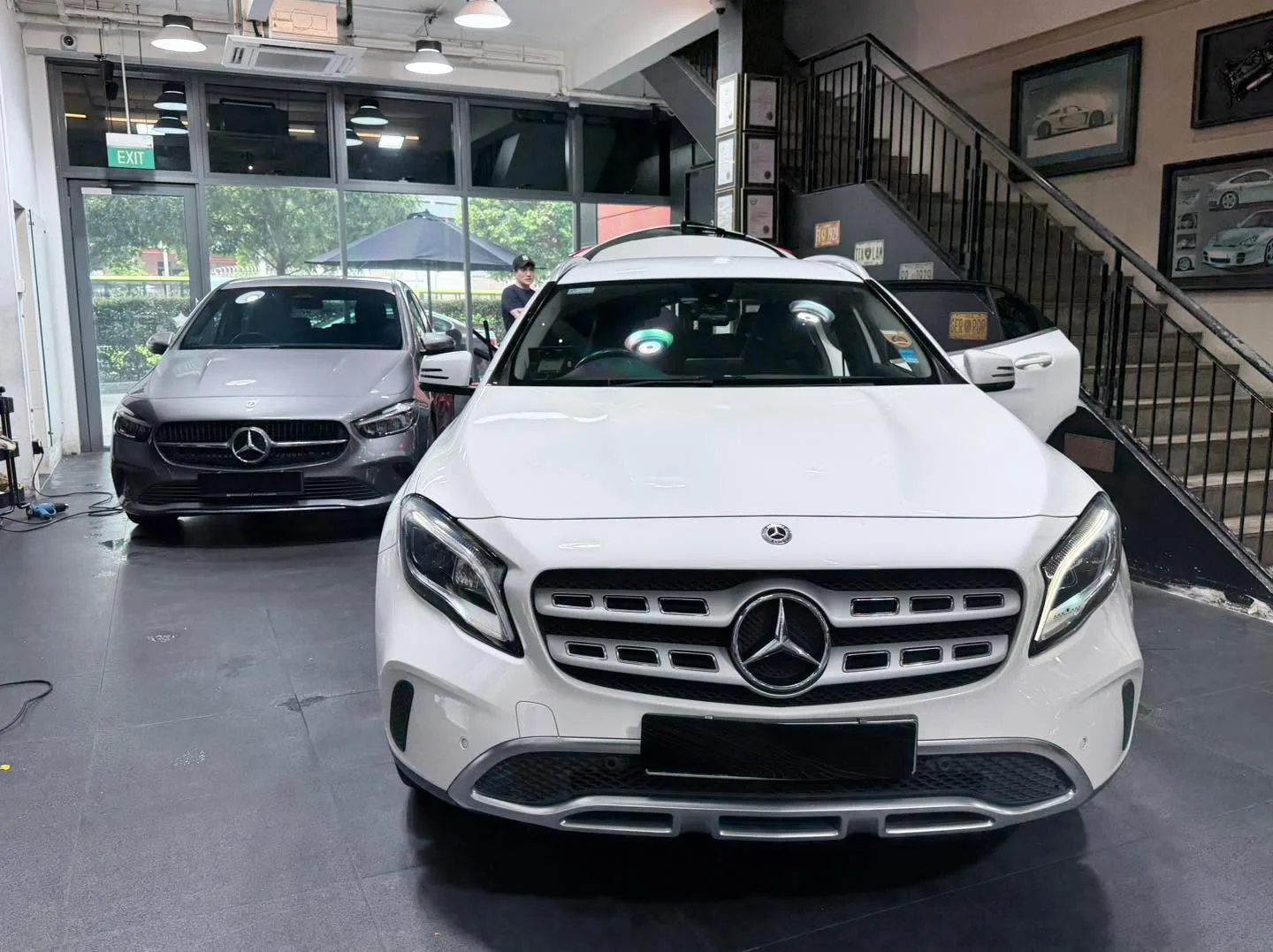A grey Mercedes-Benz SUV and a dark grey Jeep SUV parked indoors side by side.