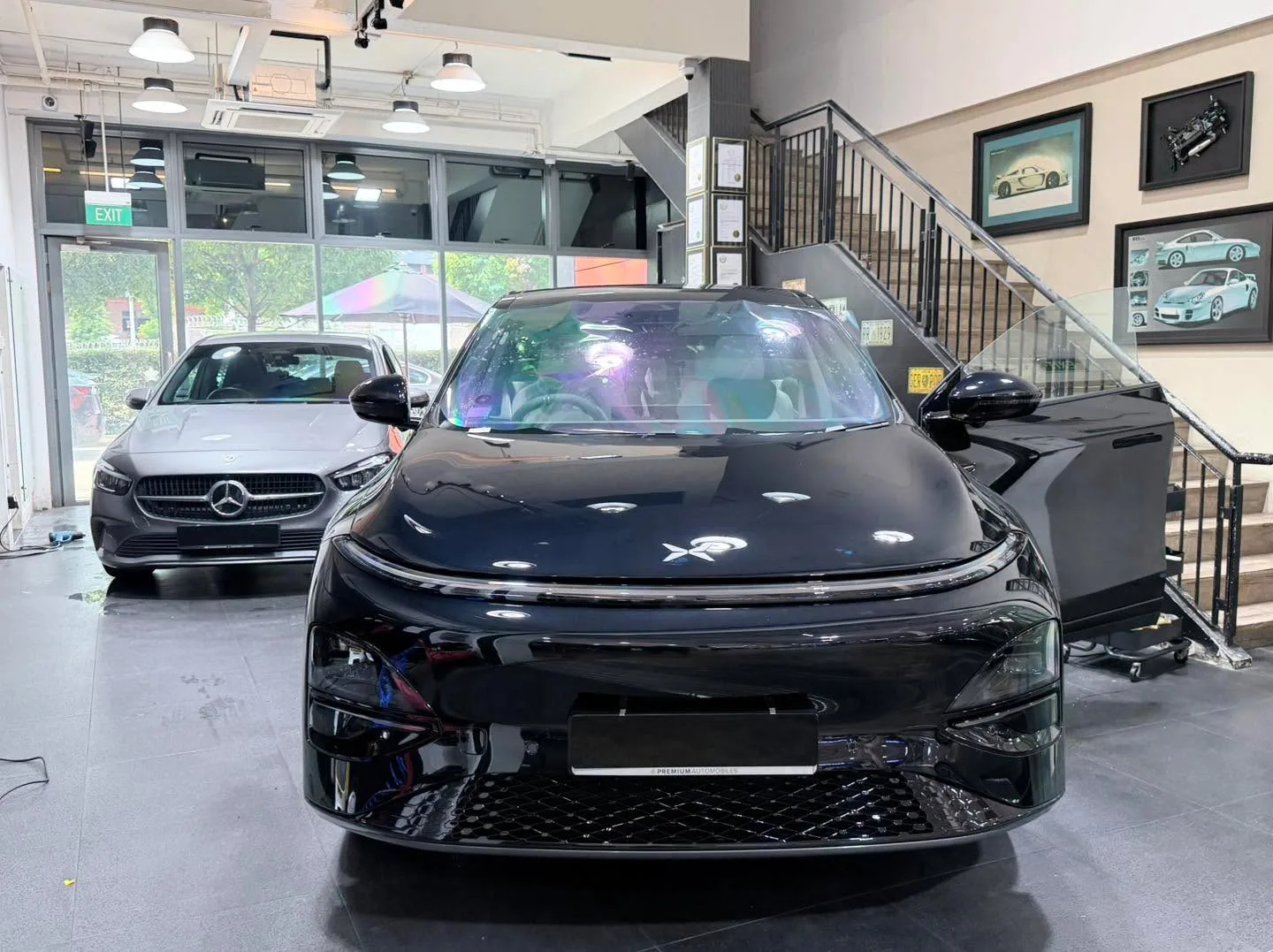 A white electric sedan and a white hatchback with round headlights parked indoors.