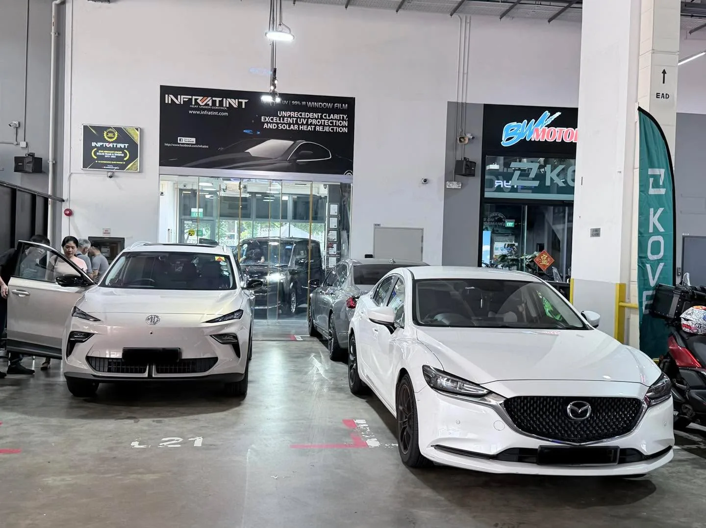 Two white saloons parked indoors, with one displaying an MG badge.