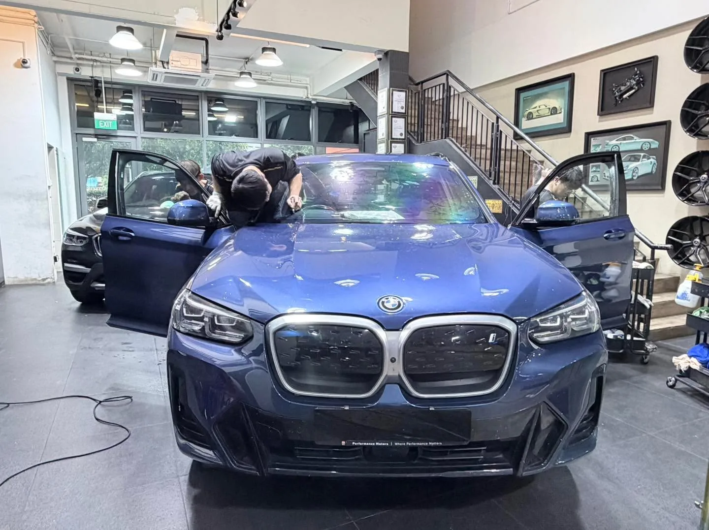 A dark blue BMW X3 SUV with doors open, undergoing tinting work.