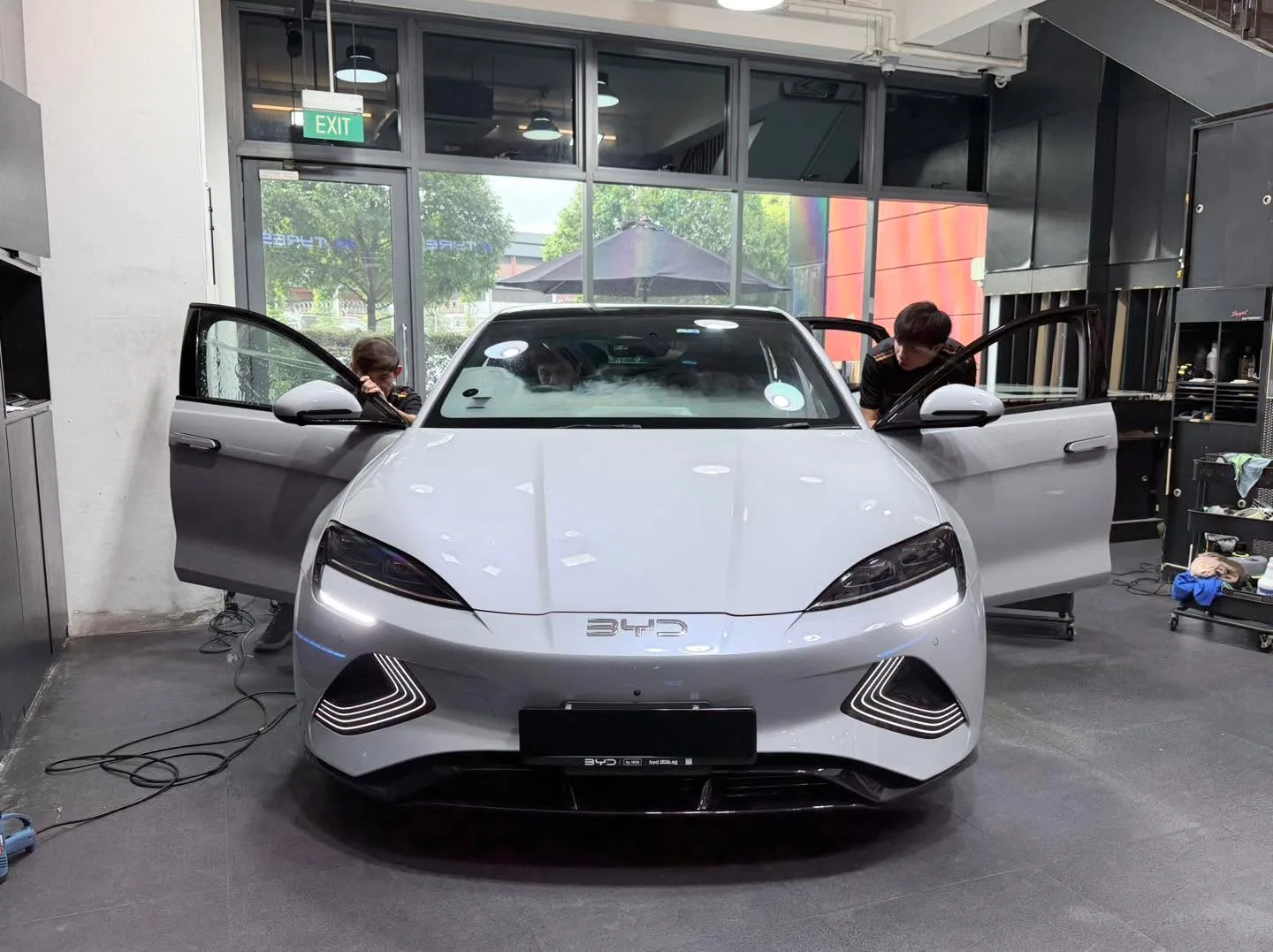 A white BYD Seal saloon with both doors open during tinting work.