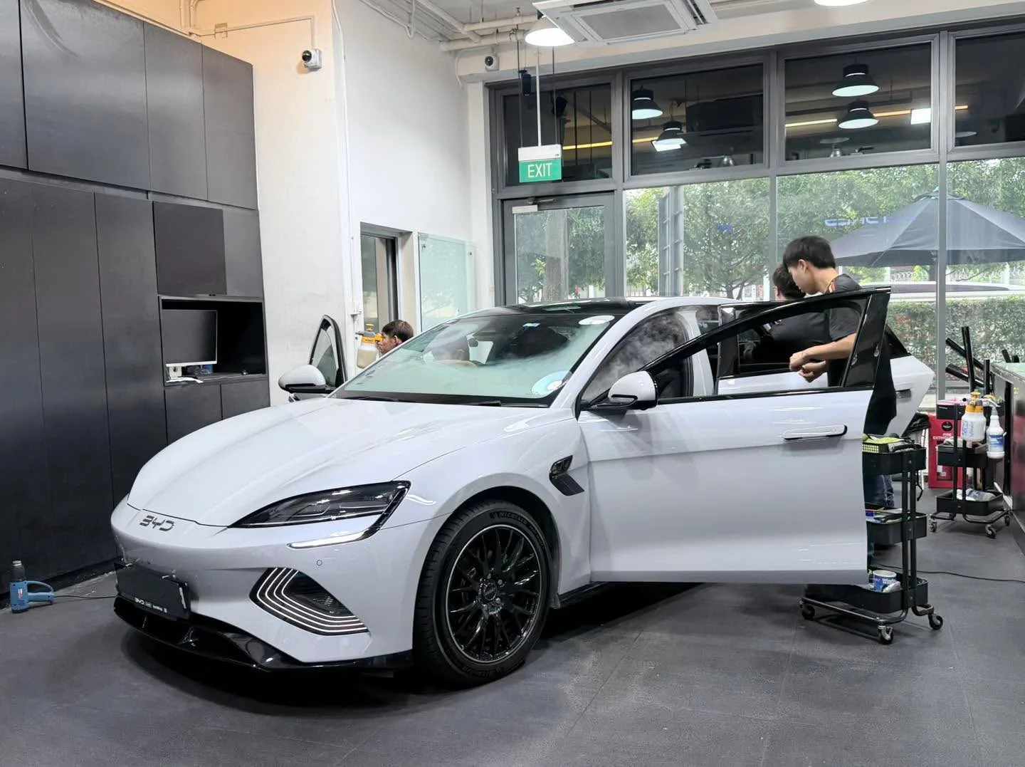 A white BYD Seal saloon with doors open in the workshop.