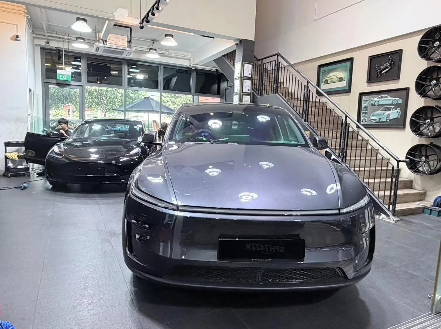 A grey hatchback and other vehicles undergoing tinting work.