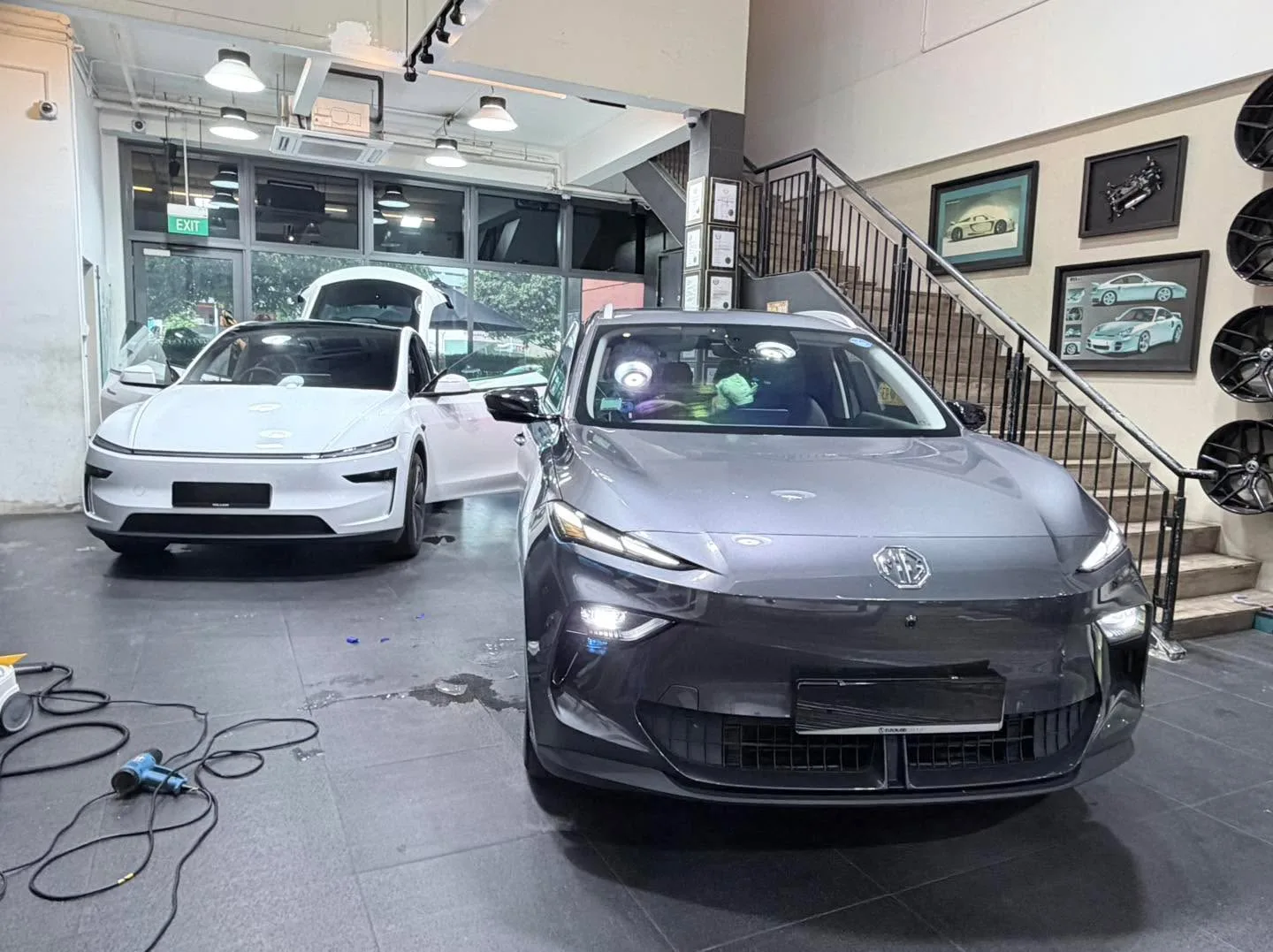 A silver hatchback and grey sedan parked in the workshop.