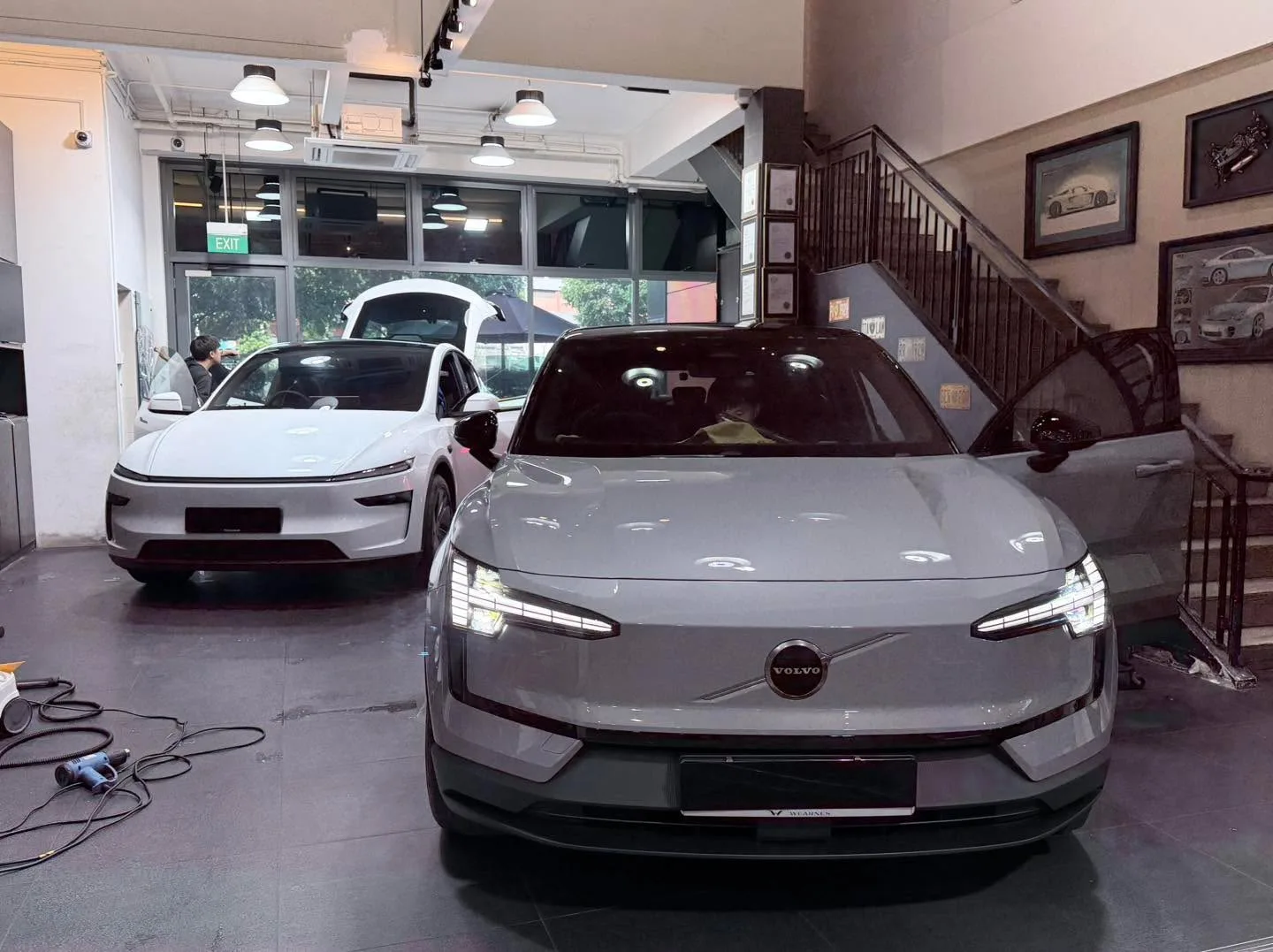 A grey sedan and white hatchback undergoing tinting.