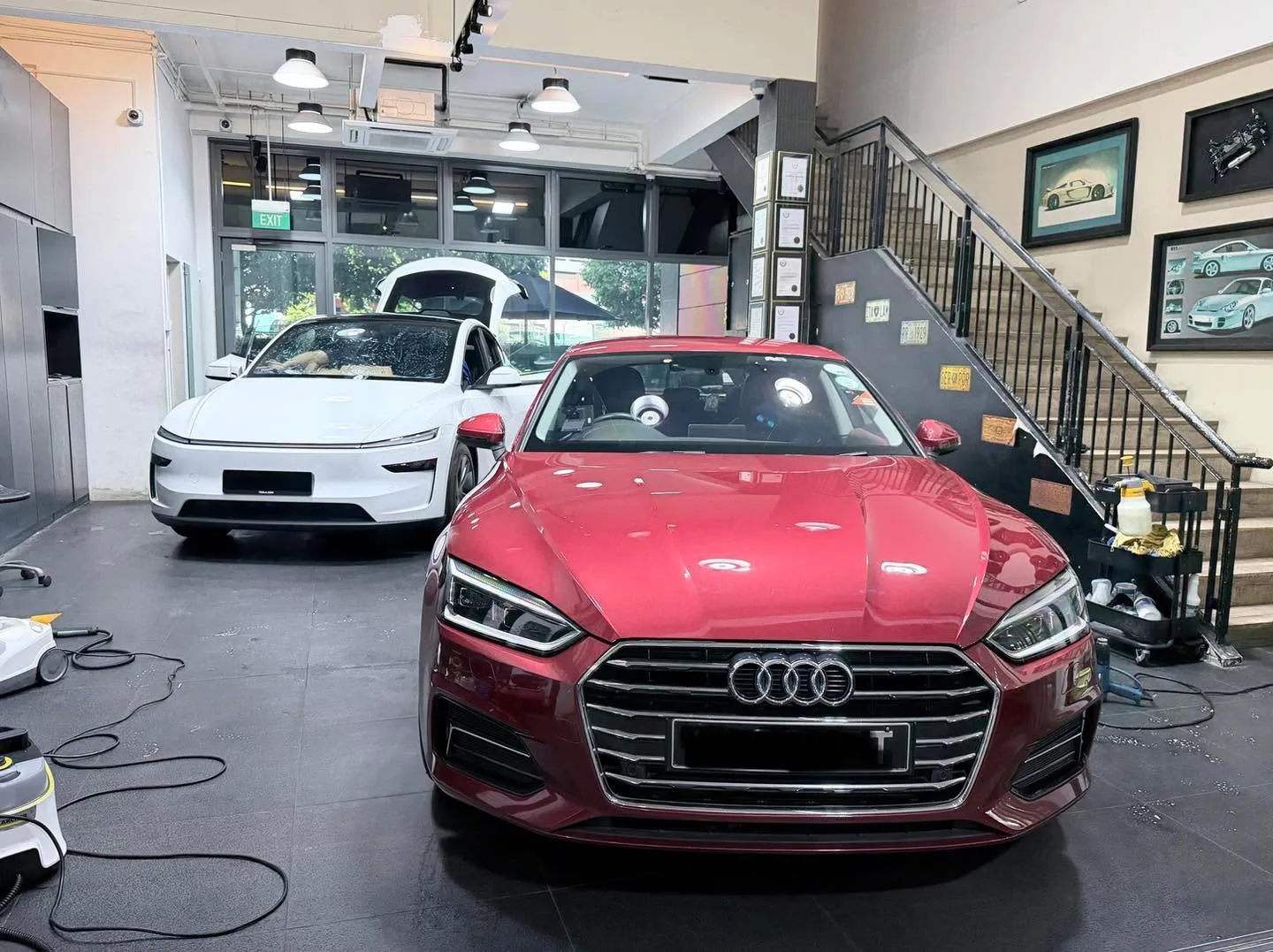 A red Audi sedan and white hatchback in the workshop.