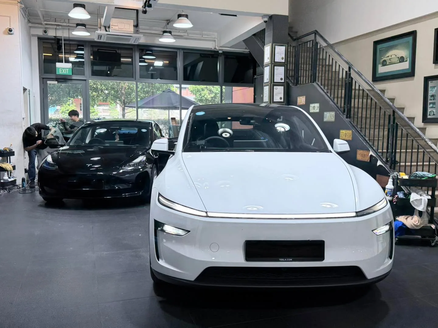 A white Tesla hatchback and silver sedan being tinted.