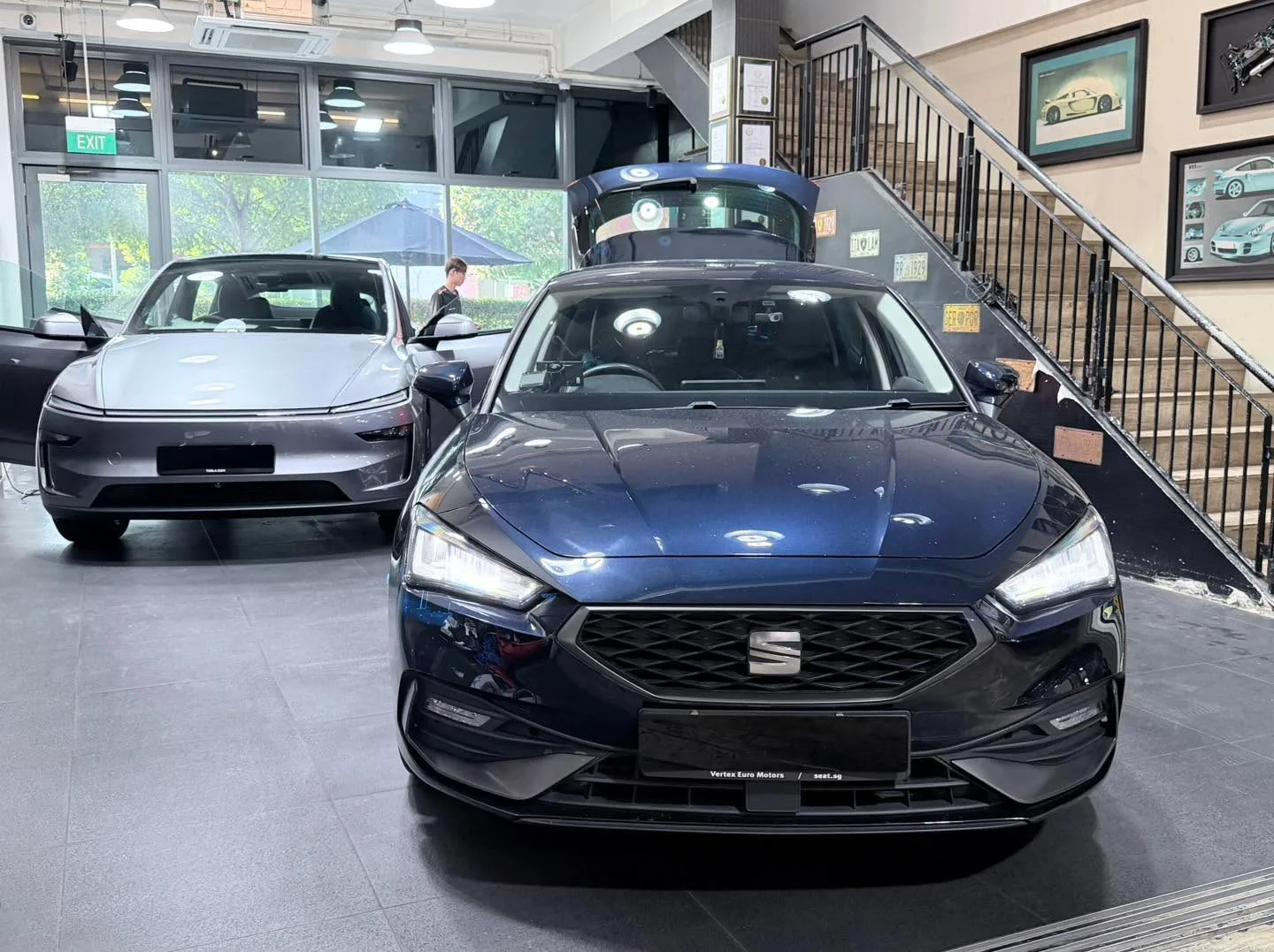 A dark blue sedan with a white hatchback and grey sedan visible behind it.
