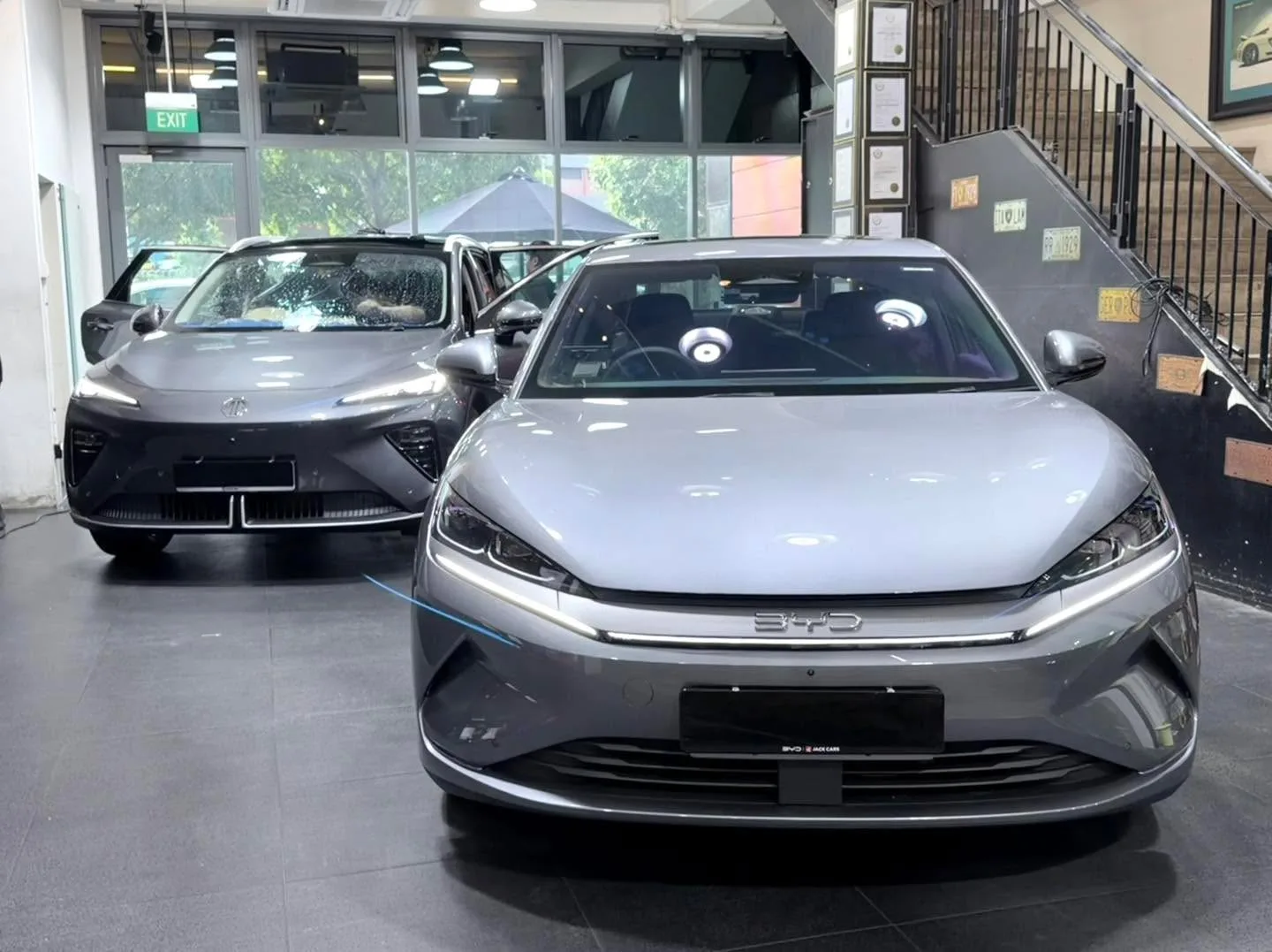 A dark grey BYD and silver BYD sedan parked indoors.
