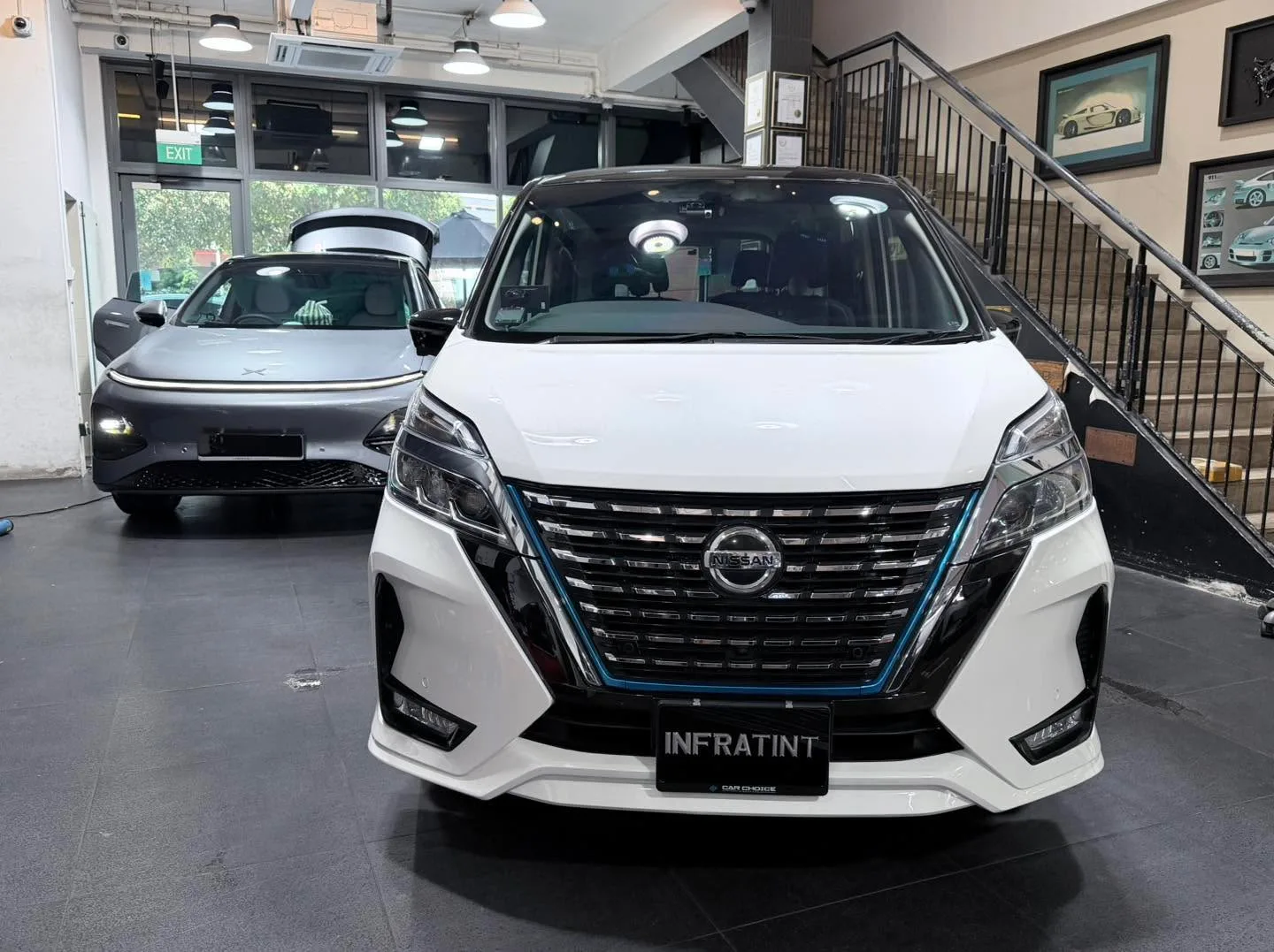 A white Nissan Serena and a dark car parked indoors.