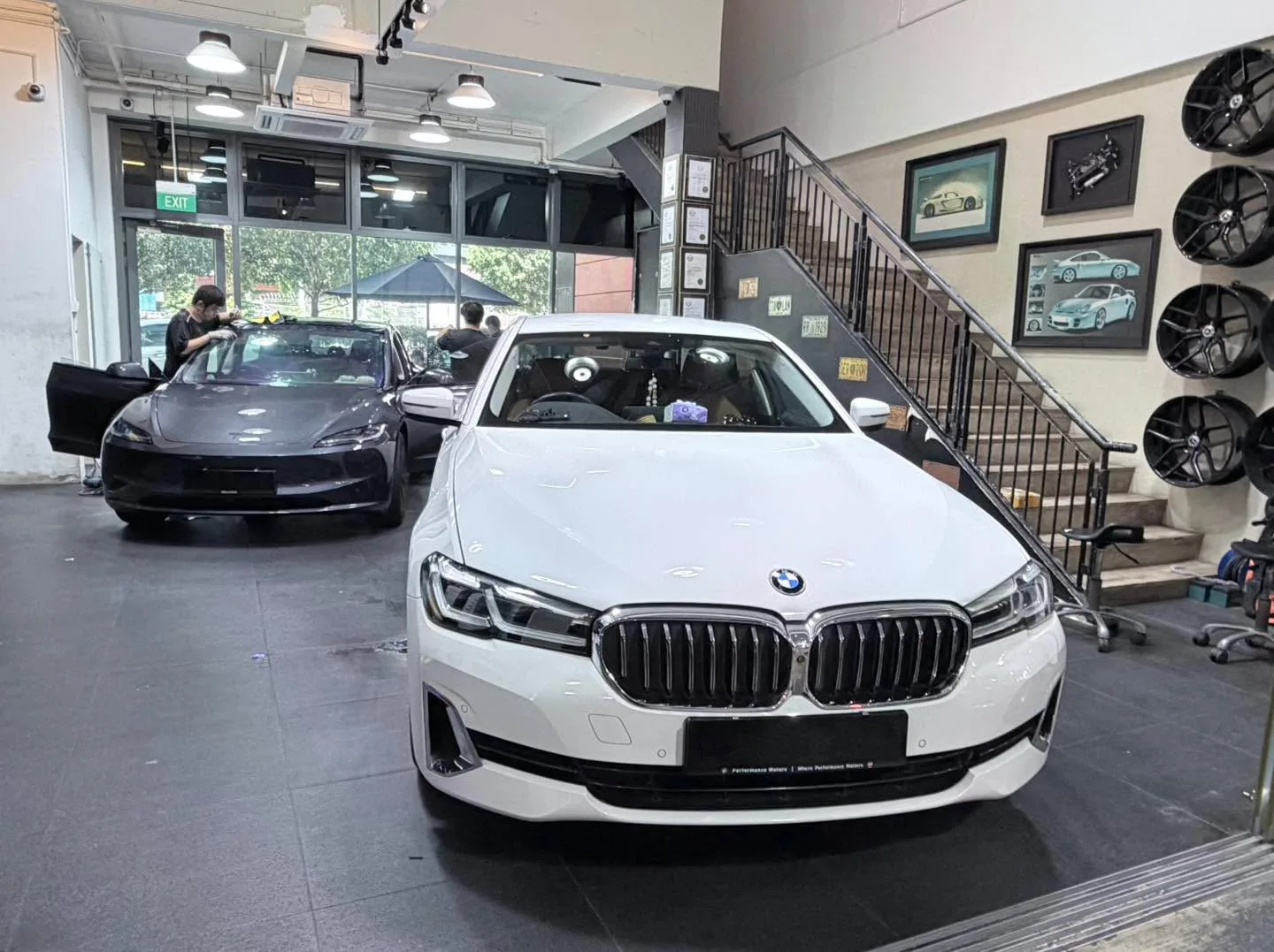 A white BMW and grey MG hatchback parked indoors.