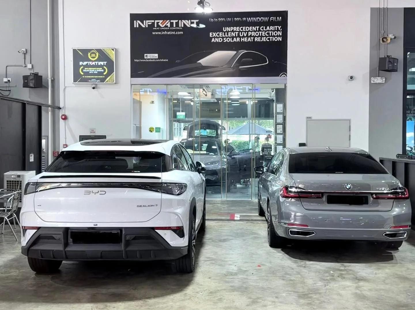 A white Jaecoo J6 SUV and a grey BMW sedan parked in the workshop.