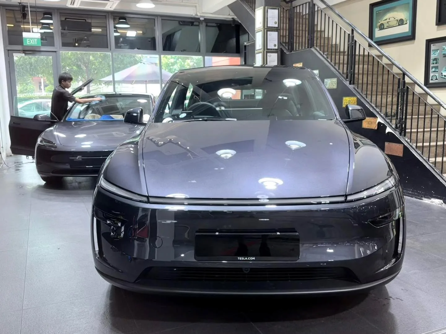 A black Tesla sedan with visible tinting in an indoor workshop.