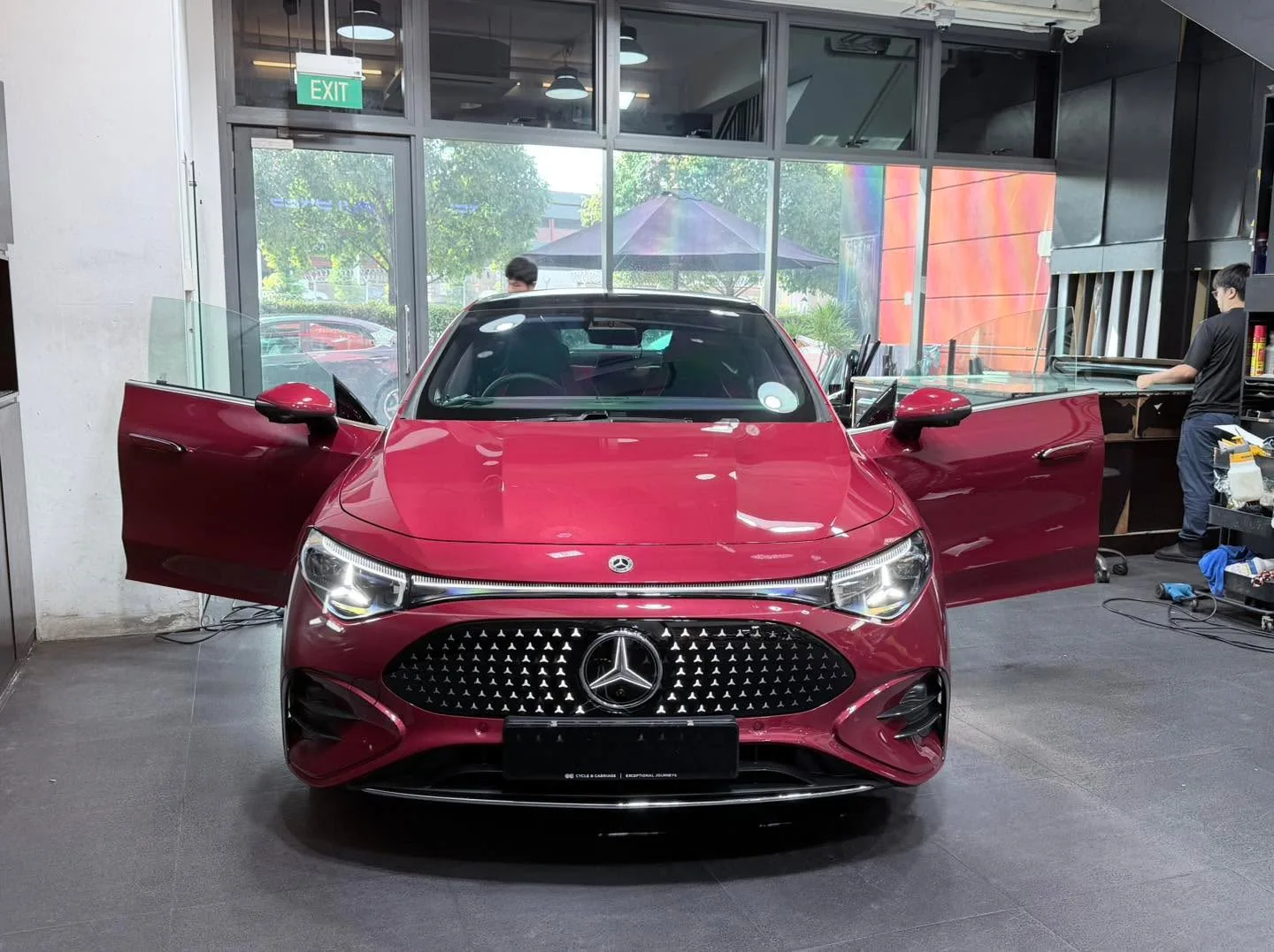 A red Mercedes-Benz sedan with both doors open, viewed from the front.