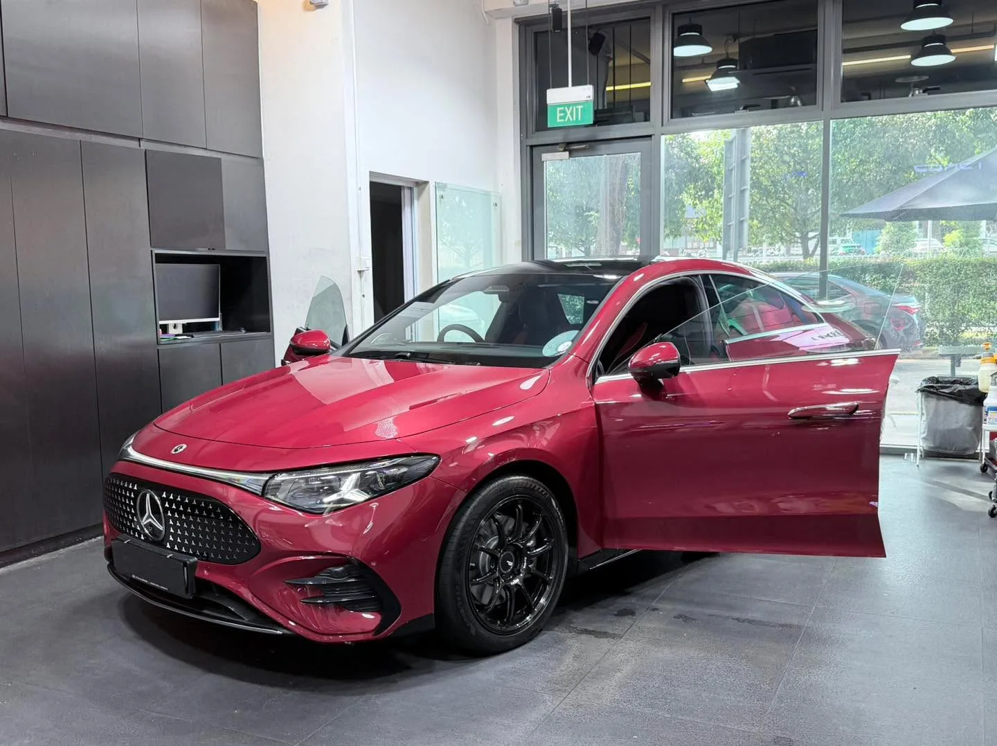 A red Mercedes-Benz sedan viewed from the side with the door open.