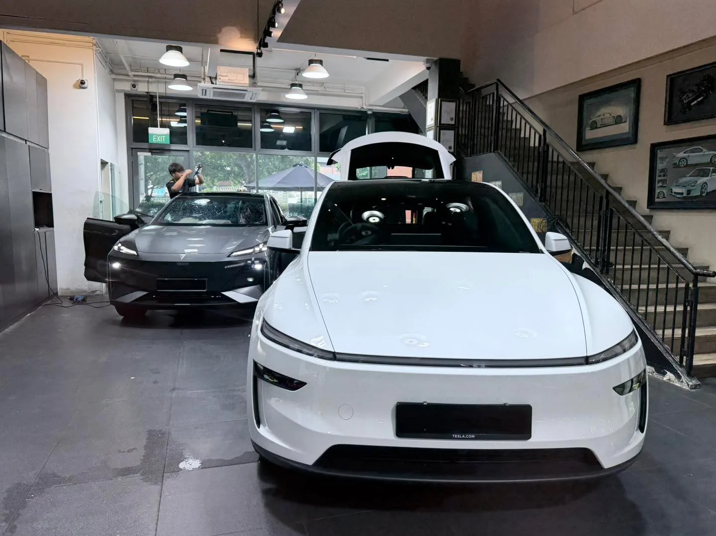 A white Tesla Model Y electric saloon with the tailgate open inside the workshop.