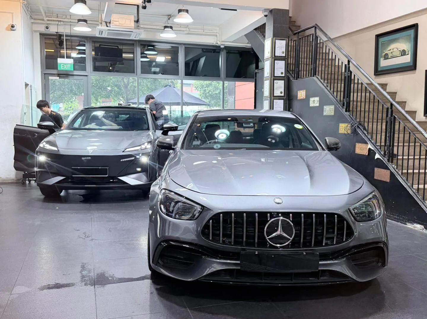 A silver Mercedes-Benz E63 saloon and a dark-coloured Tesla parked inside the workshop.