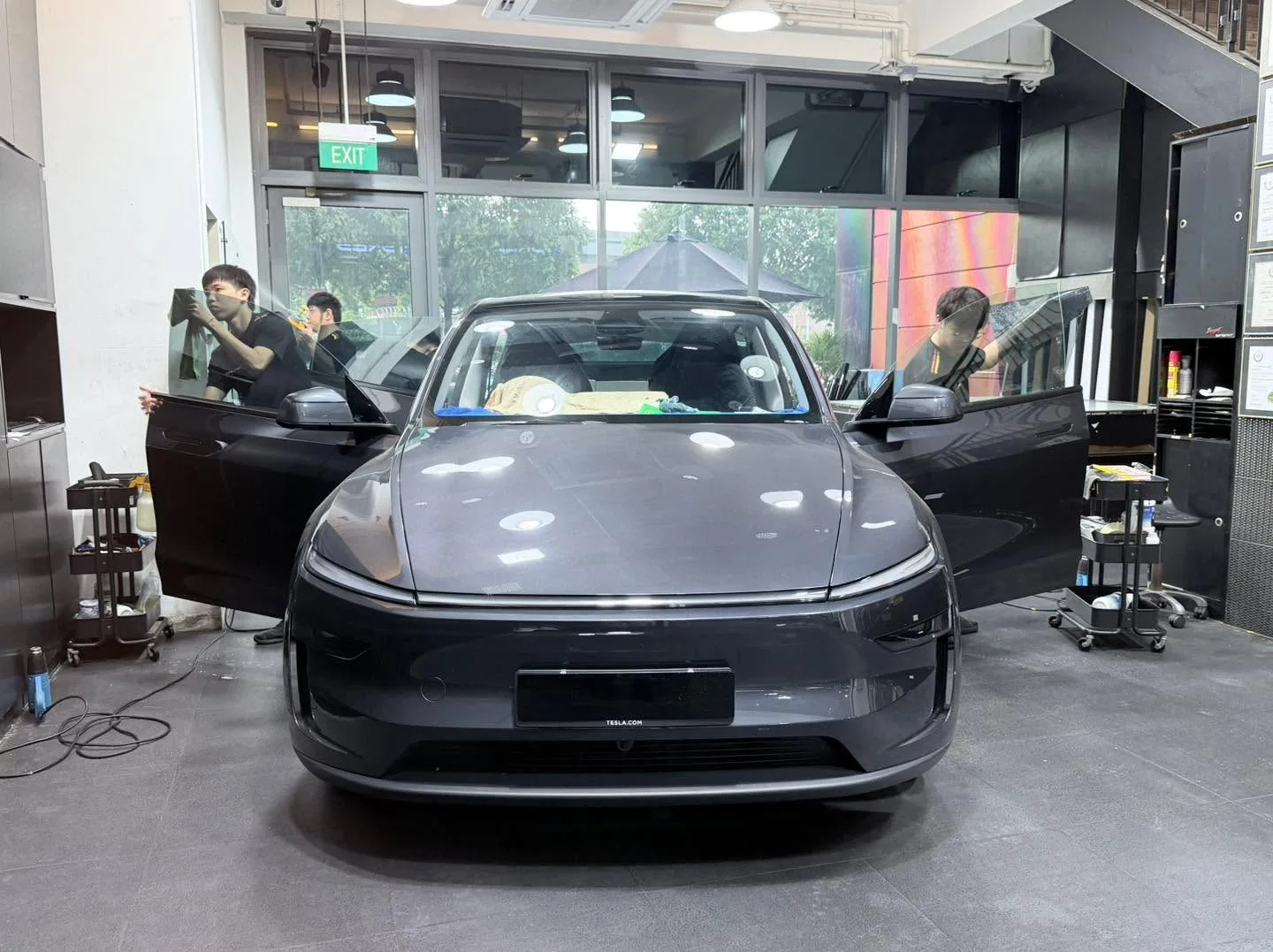 A dark-coloured Deepal S07 with doors open being worked on by staff inside the workshop.