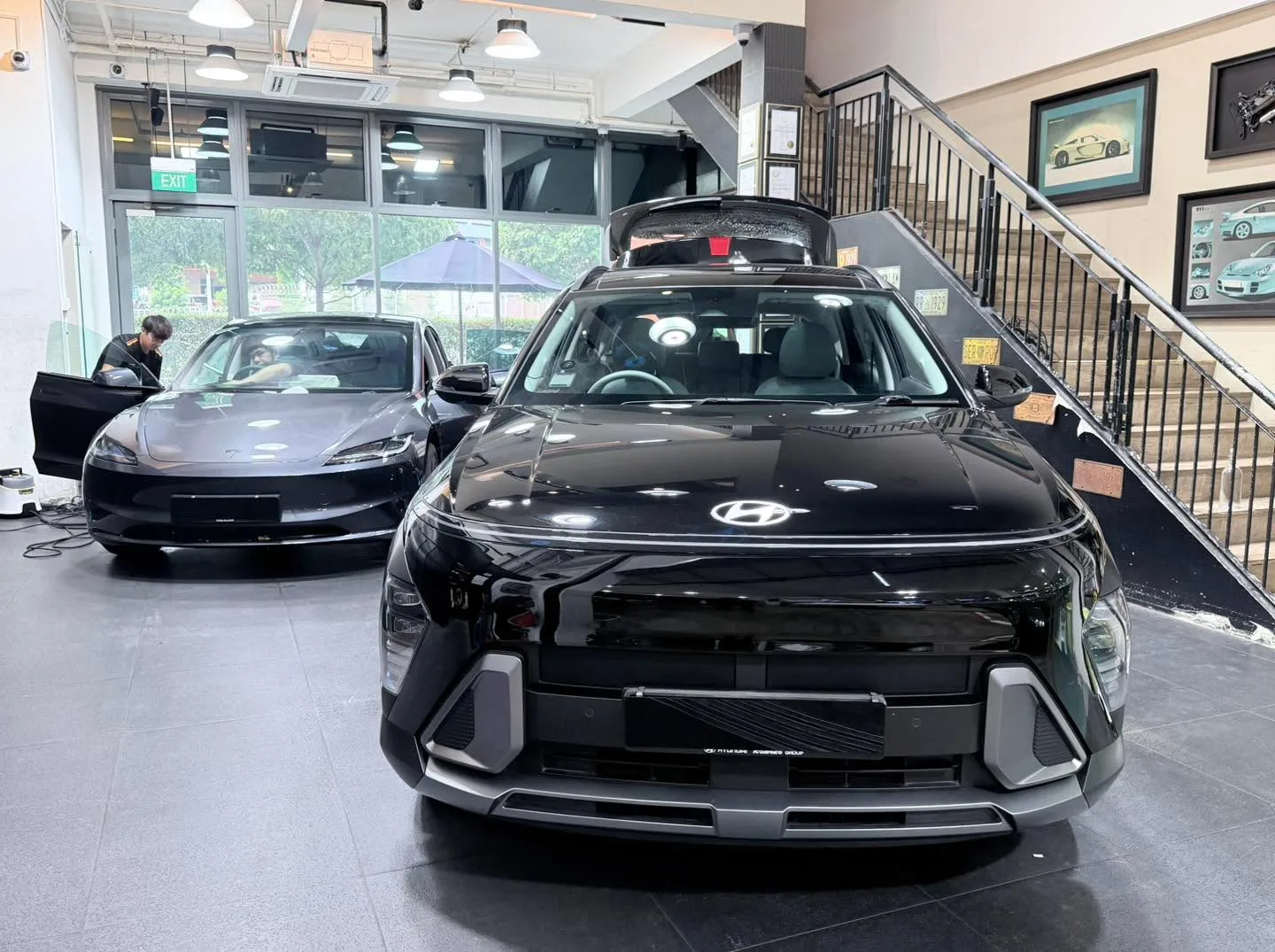 Black Tesla SUV with roof rack and distinctive front styling in workshop space.