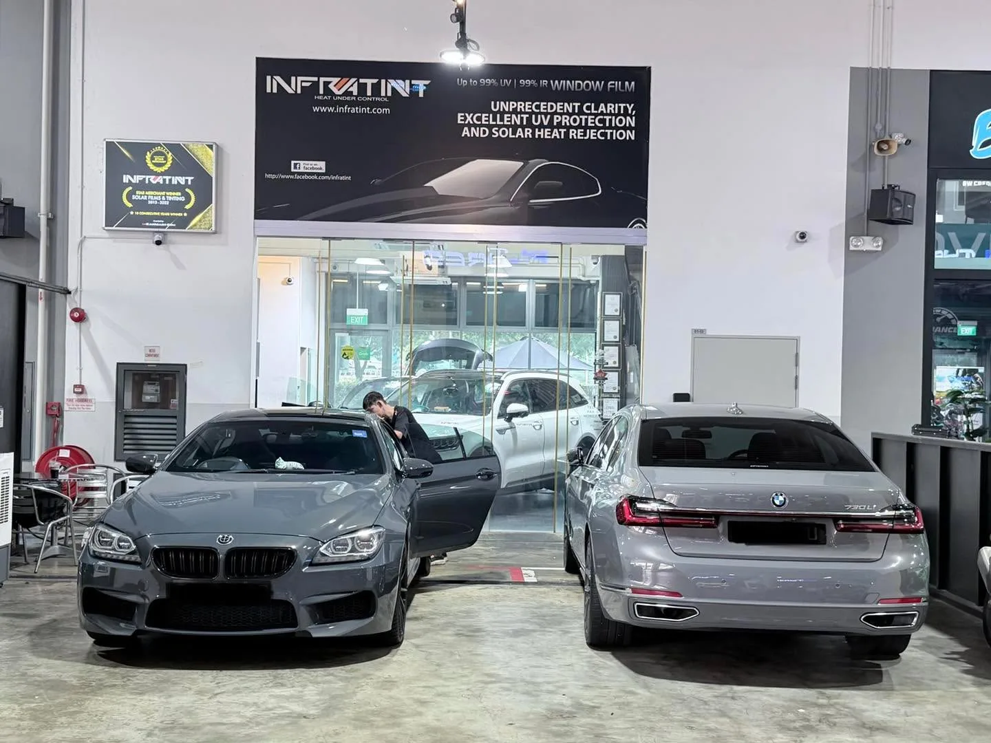 A grey BMW coupe and a silver BMW sedan parked outside the workshop.