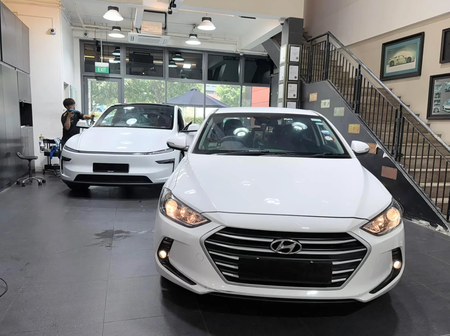 A white Hyundai sedan and a white Tesla sedan parked together indoors.