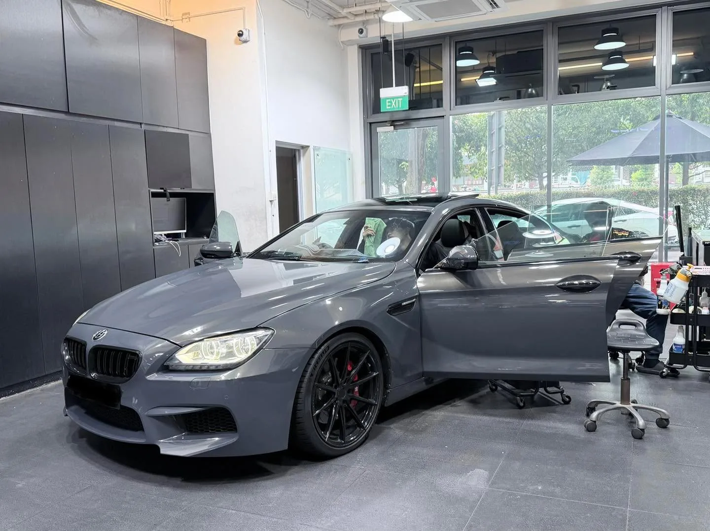 A white Tesla sedan with doors raised open, parked indoors.