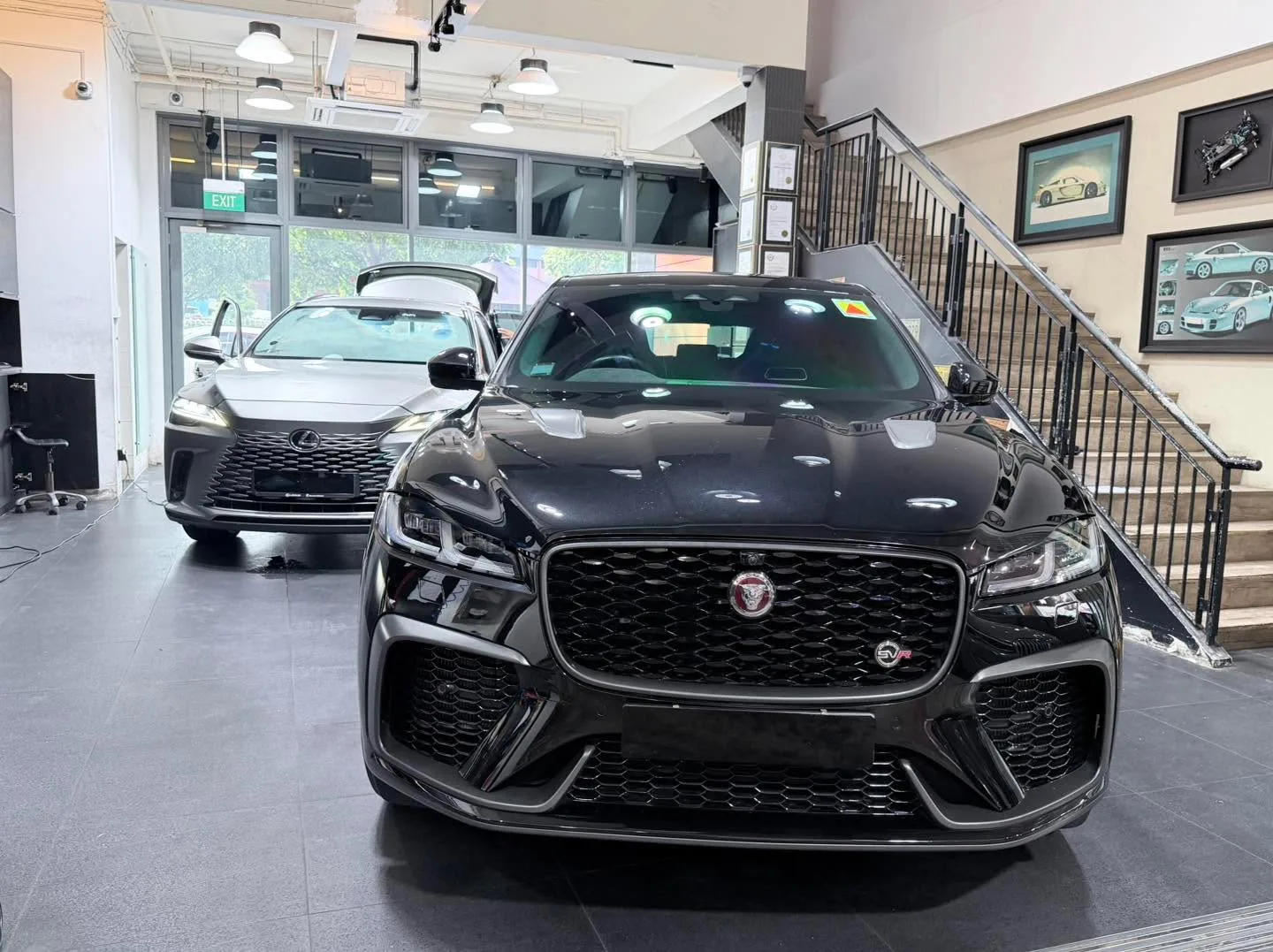 A black Jaguar F-Pace SVR with distinctive grille and silver headlights inside a workshop.