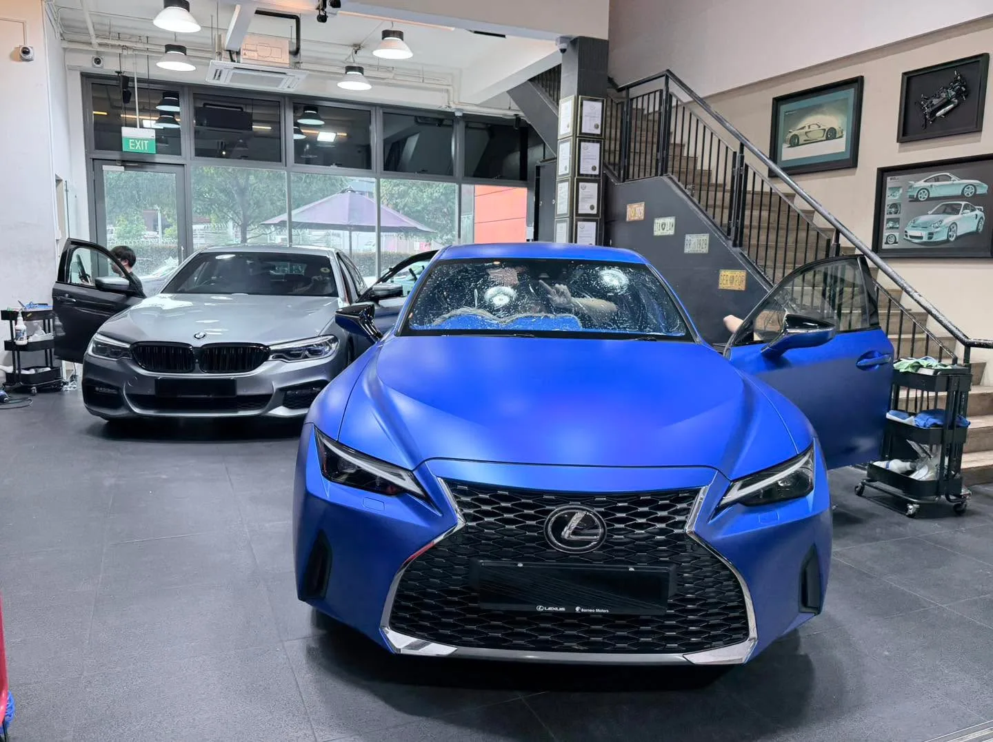 Blue Lexus IS300 and grey BMW sedan parked indoors.