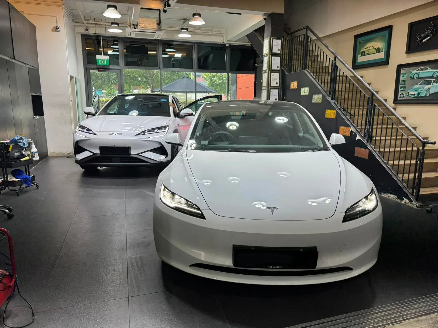 White Tesla saloon and white Tesla with gull-wing doors in workshop.