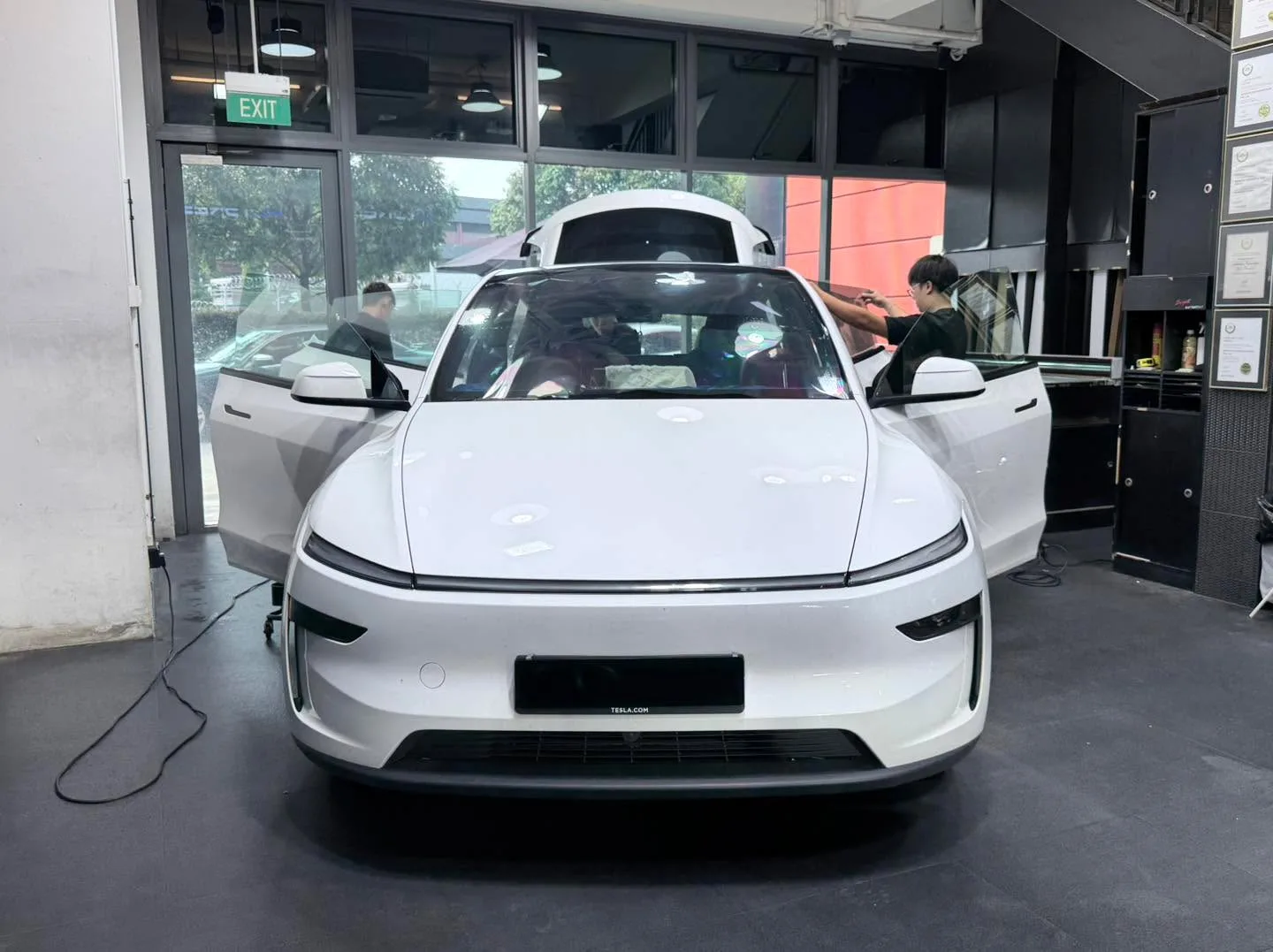 White Tesla saloon being tinted with technicians applying film.