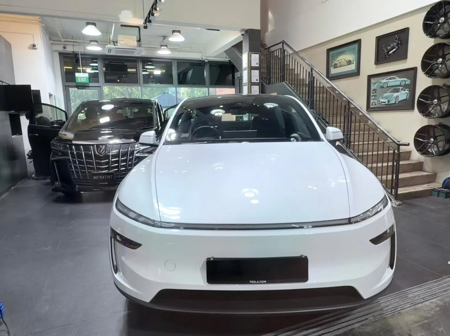 A white Tesla saloon viewed from the front.