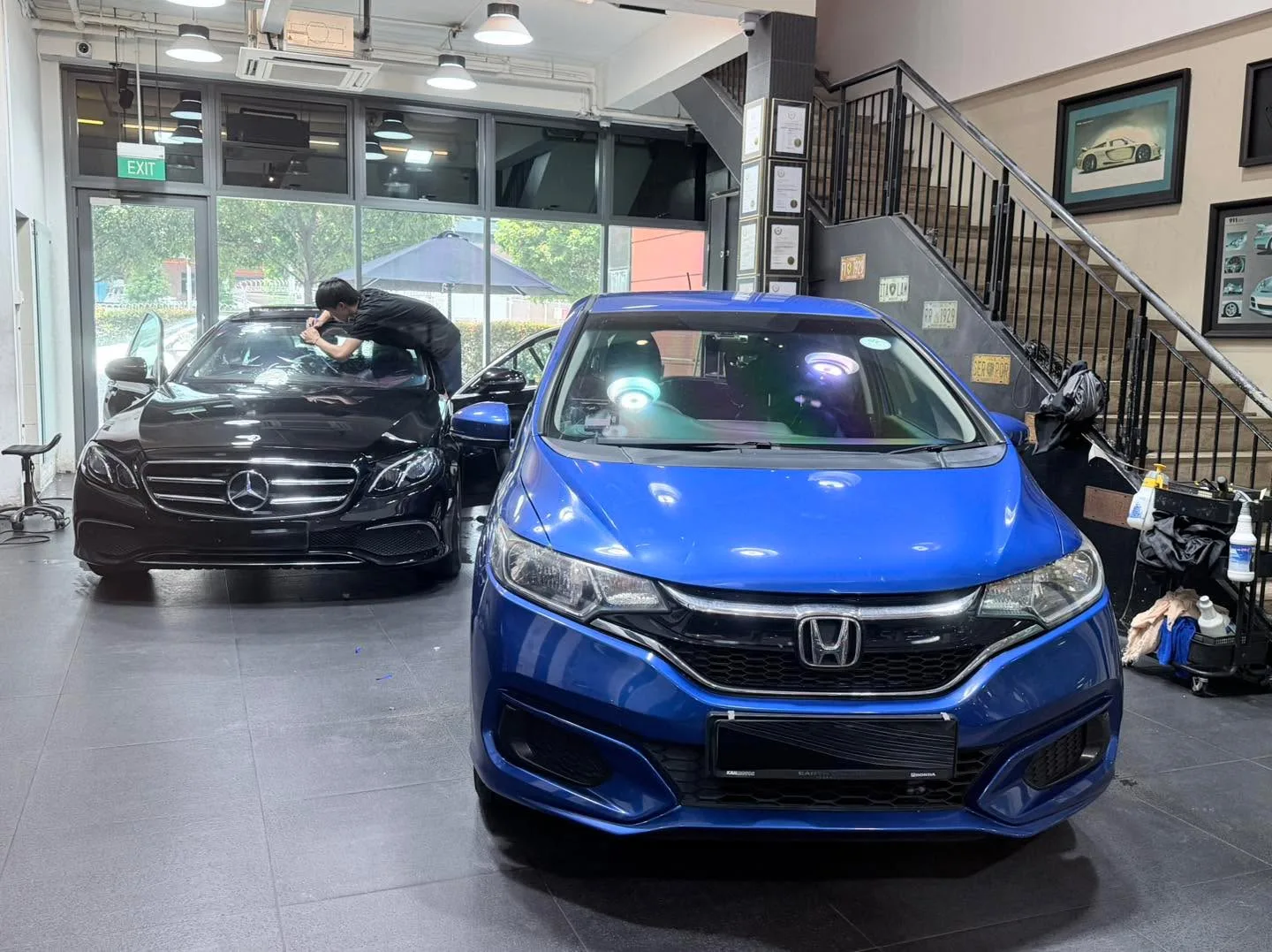 A blue BMW and a black Mercedes-Benz saloon inside the workshop.
