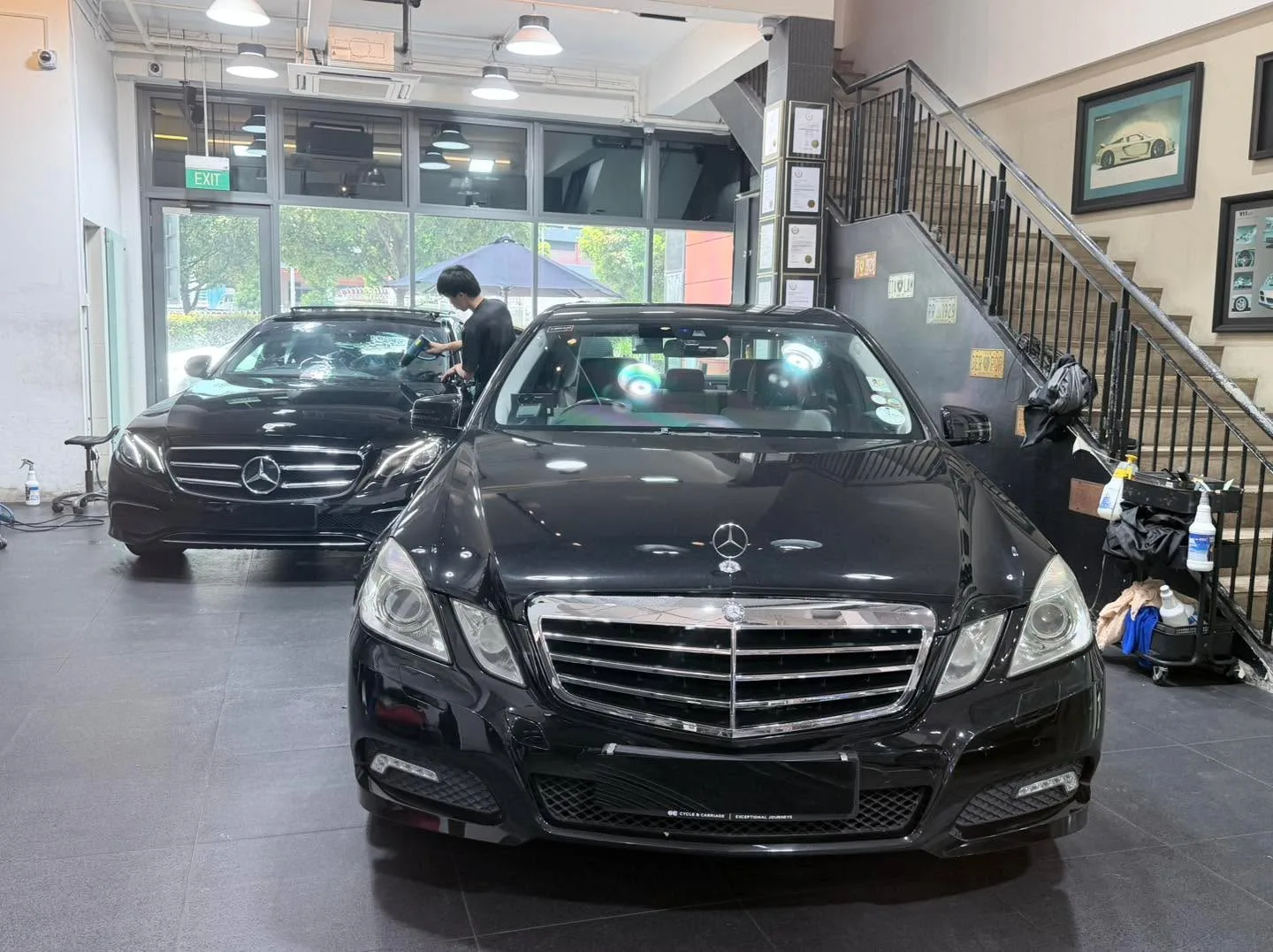 Two black Mercedes-Benz saloons parked inside the workshop.