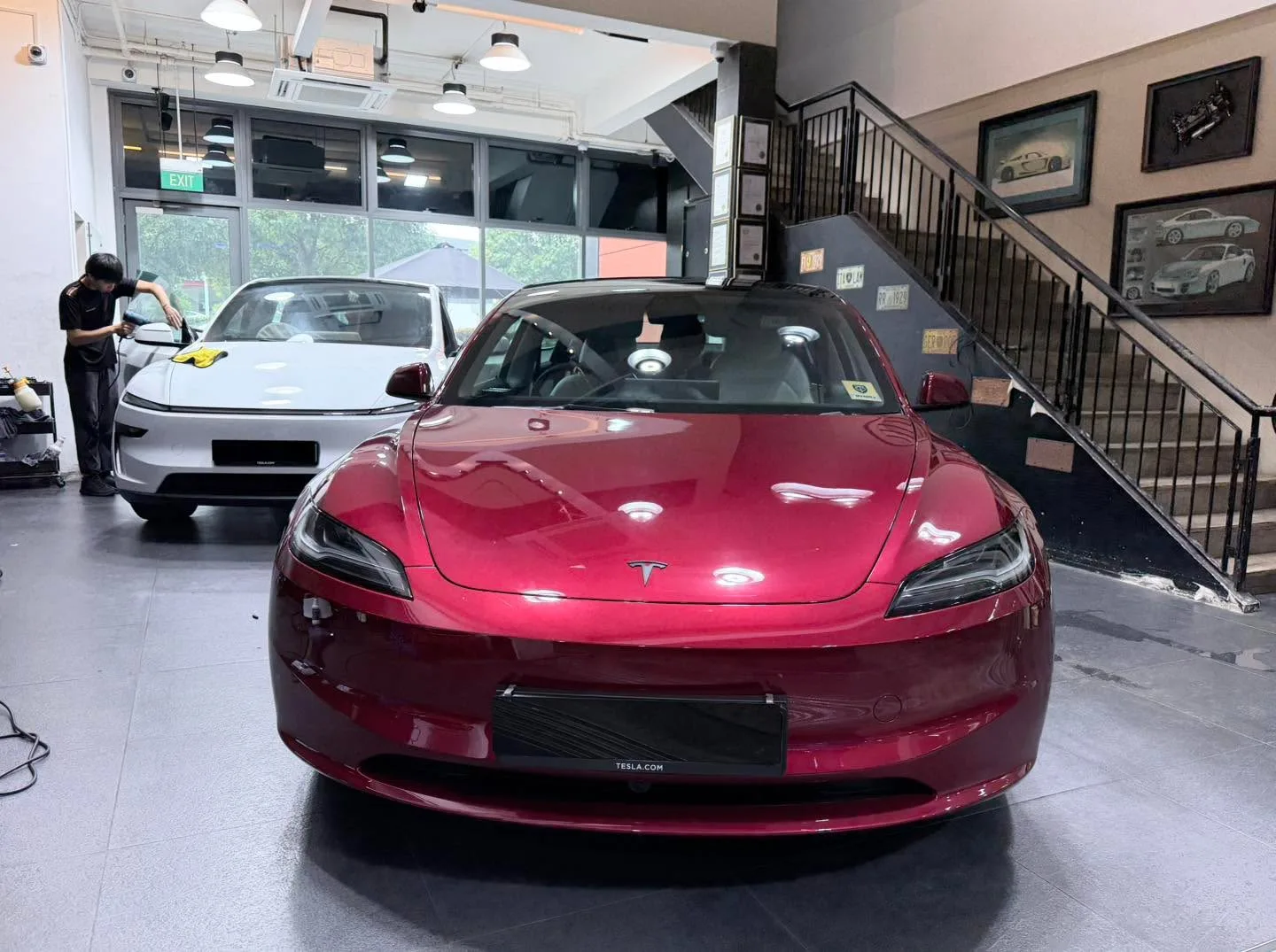 A bright red Tesla saloon viewed from the front in the workshop.