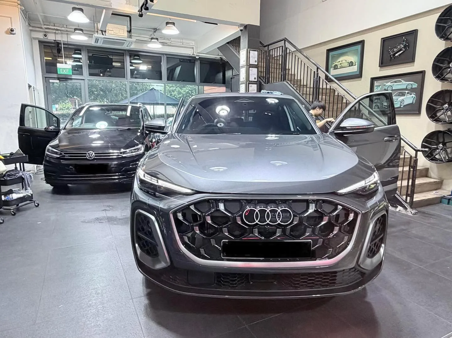 A grey Audi Q5 SUV viewed from the front, with a black Volkswagen saloon behind it.