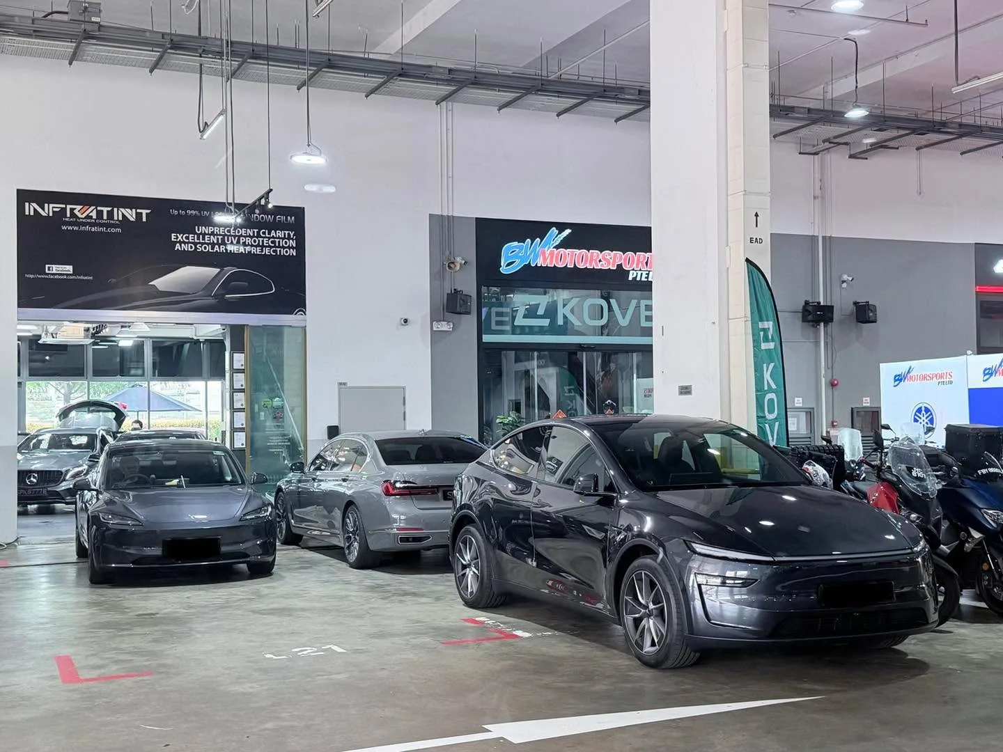 Three dark-coloured cars parked indoors at the workshop.