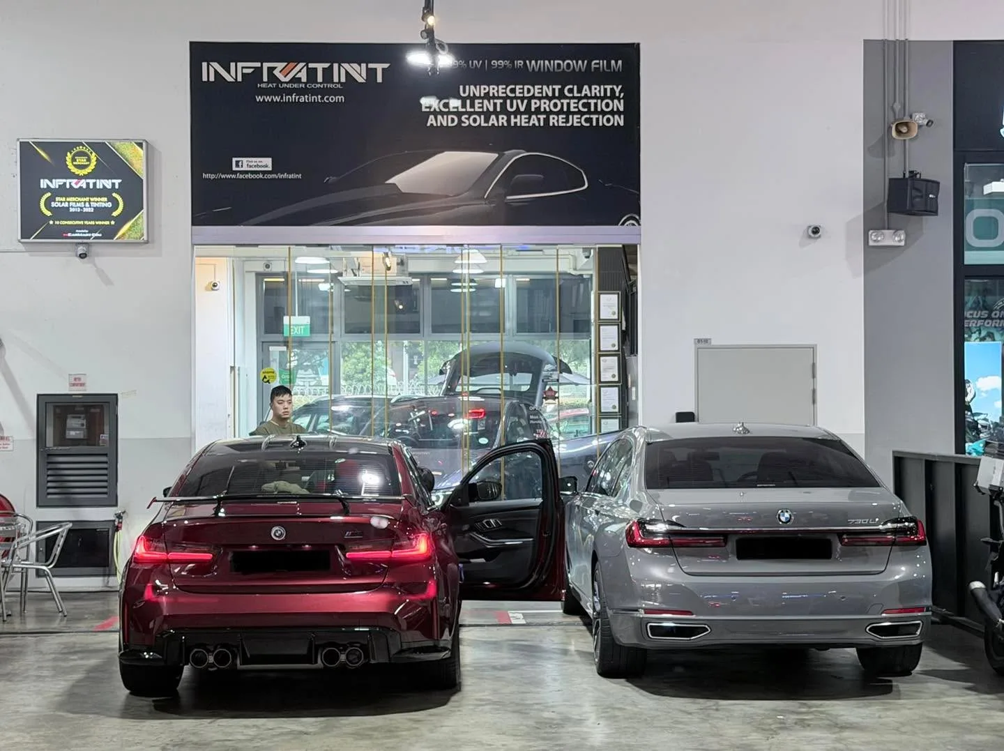 A dark red saloon with doors open, and a grey saloon to its right, in the workshop.