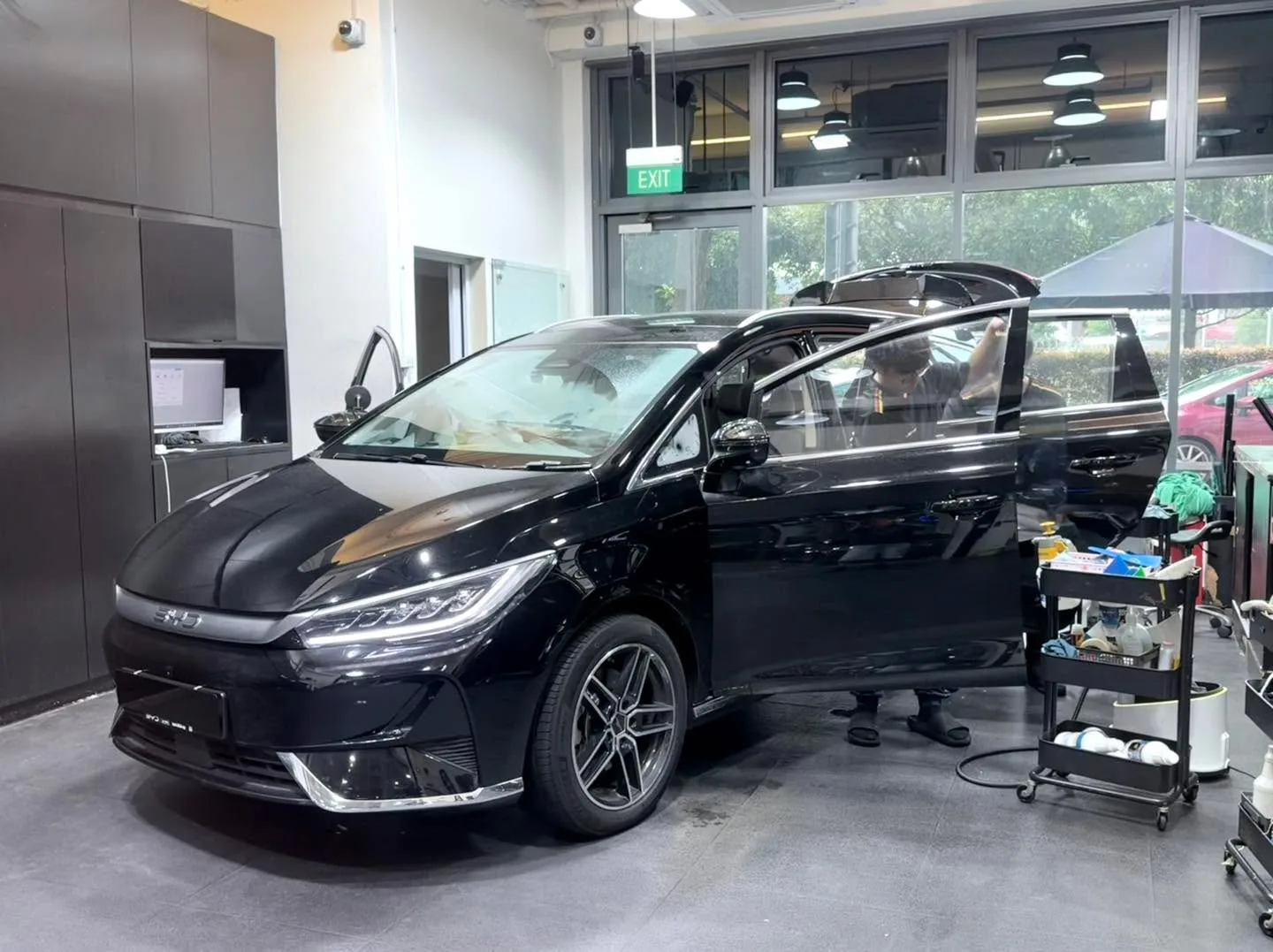 A black BYD multi-purpose vehicle with passenger door open, in the workshop.