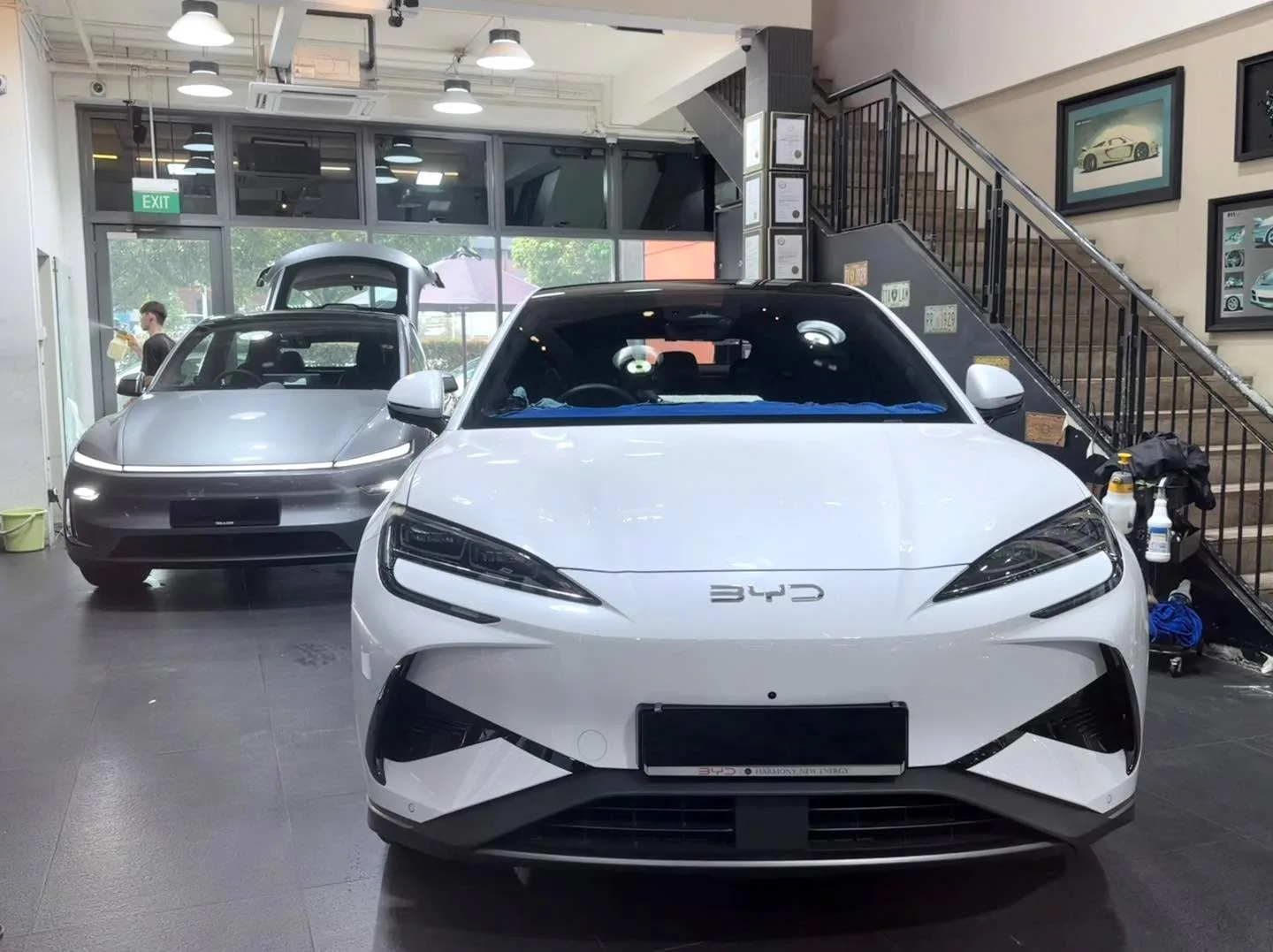 White BYD Sealion 7 and a grey car with doors open during tinting work.