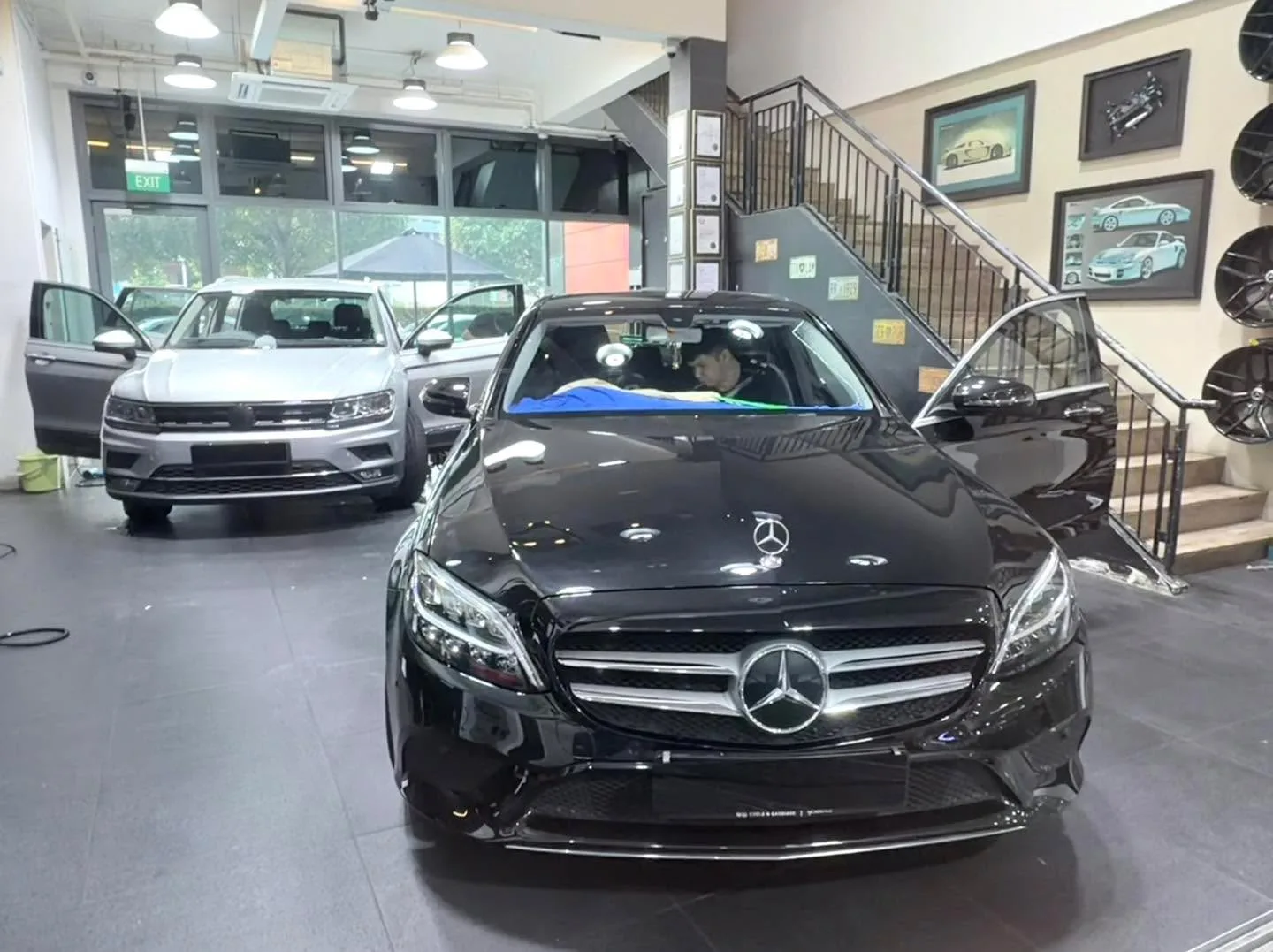 Black Mercedes-Benz C-Class with doors open, technician applying tint.