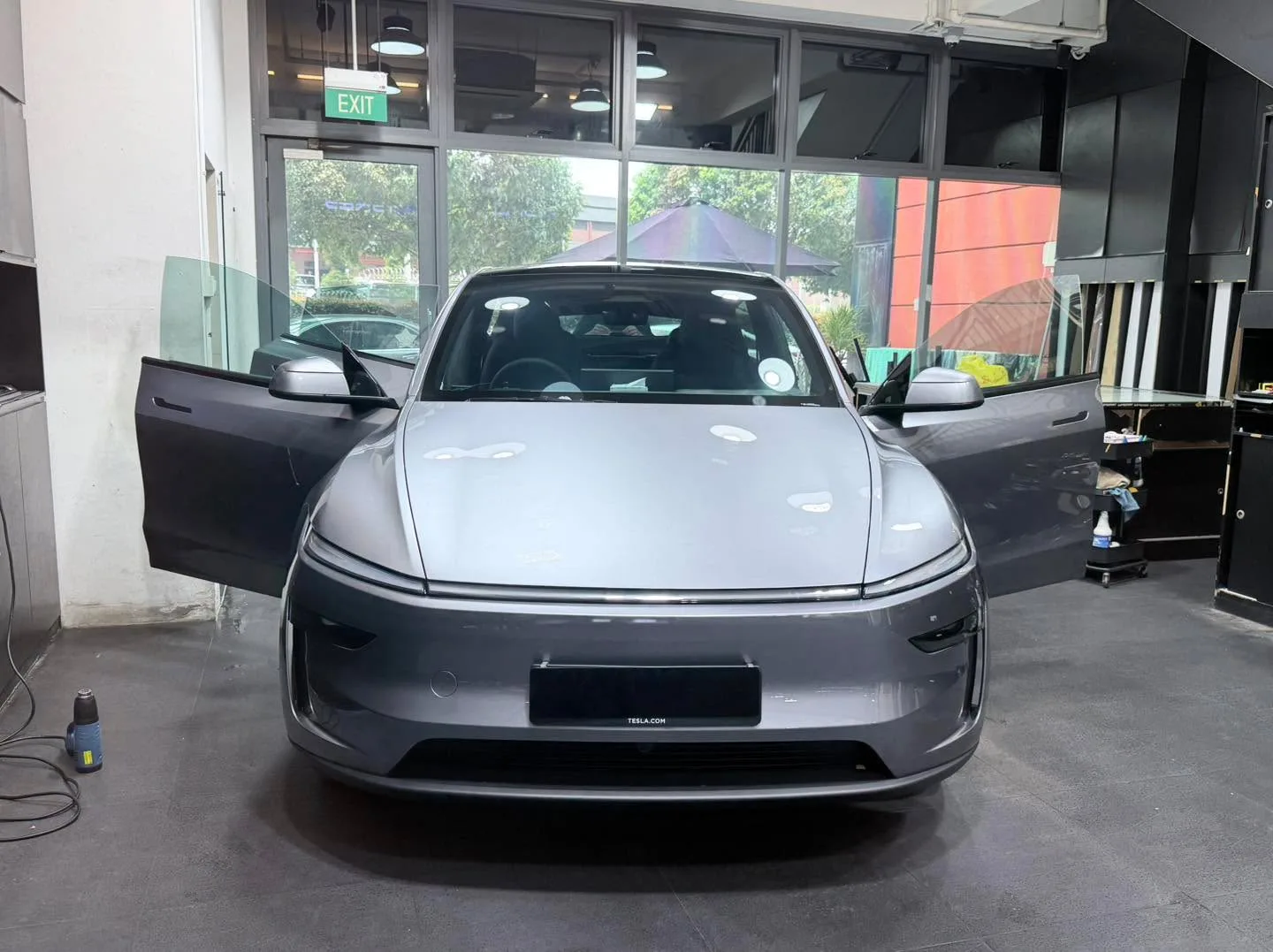 White Tesla electric saloon with doors open at the workshop.