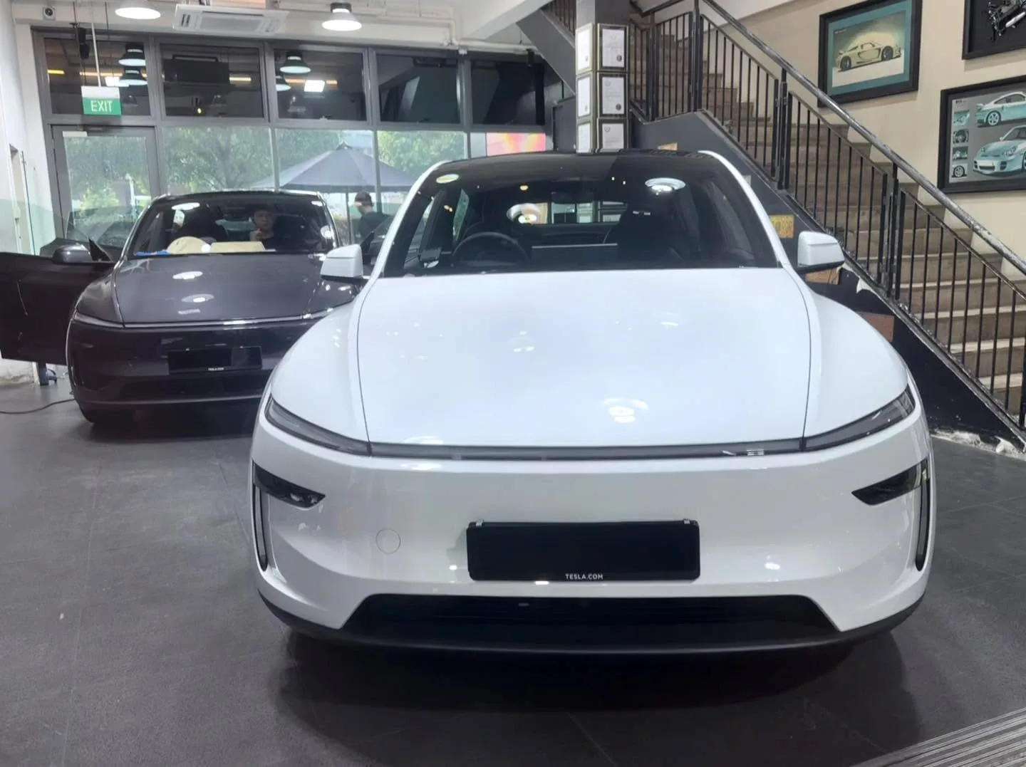 A white Tesla Model Y viewed from the front with yellow-orange headlight accents.