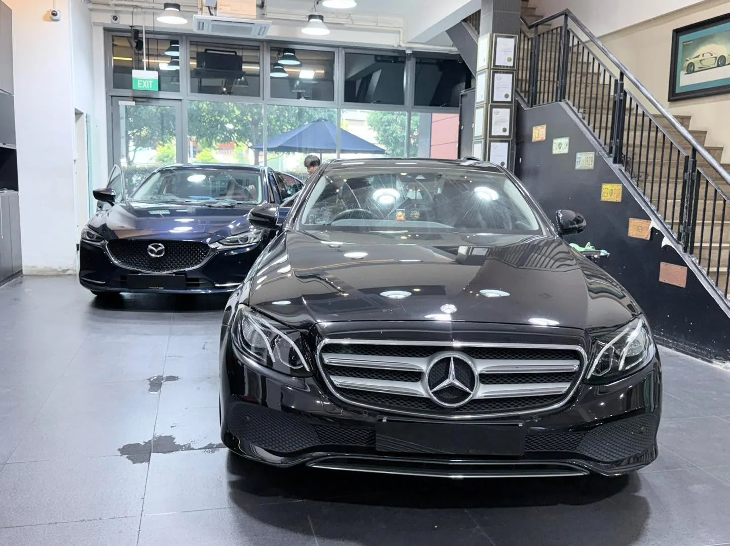 A white Mercedes-Benz compact SUV and a black Mazda sedan parked side by side indoors.