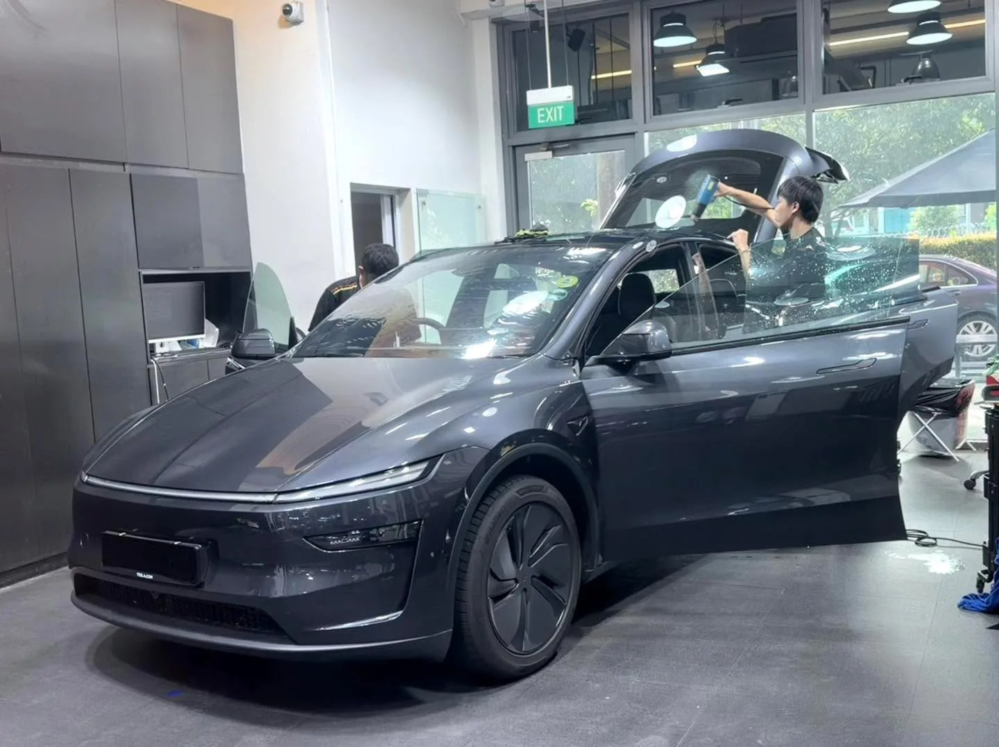 A dark grey IM Motors IM6 SUV with open doors as staff apply window film.