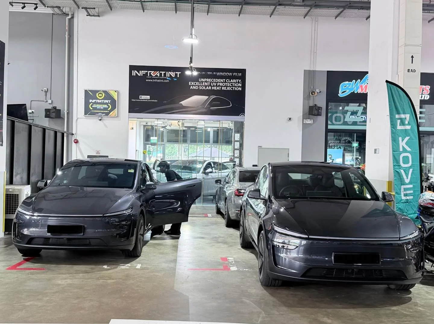 A dark grey Avatr sedan, a black sedan with door open, and a dark grey sedan parked in the workshop.