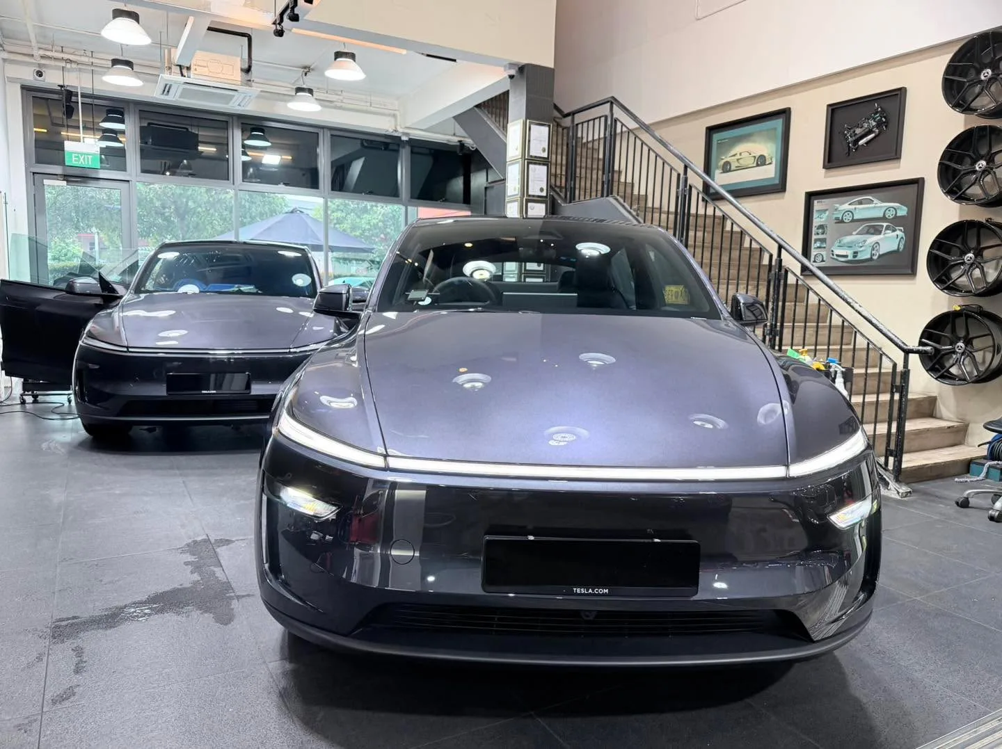 A black Tesla electric sedan and a white BYD sedan parked indoors at the workshop.