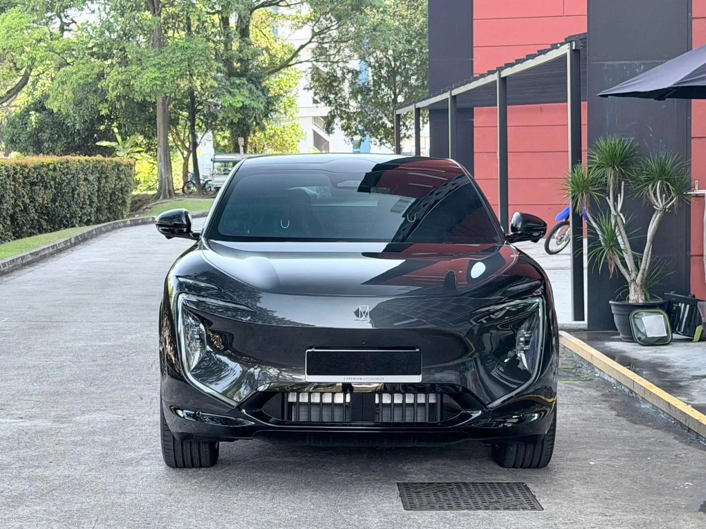 A black Avatr 07 SUV parked on a driveway outside a red and black building with landscaping.