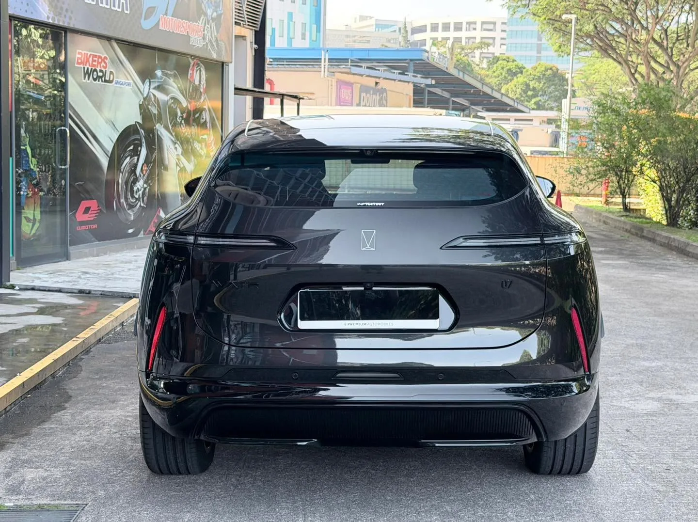 Rear view of a black Avatr 07 parked on a street near a motorcycle shop.